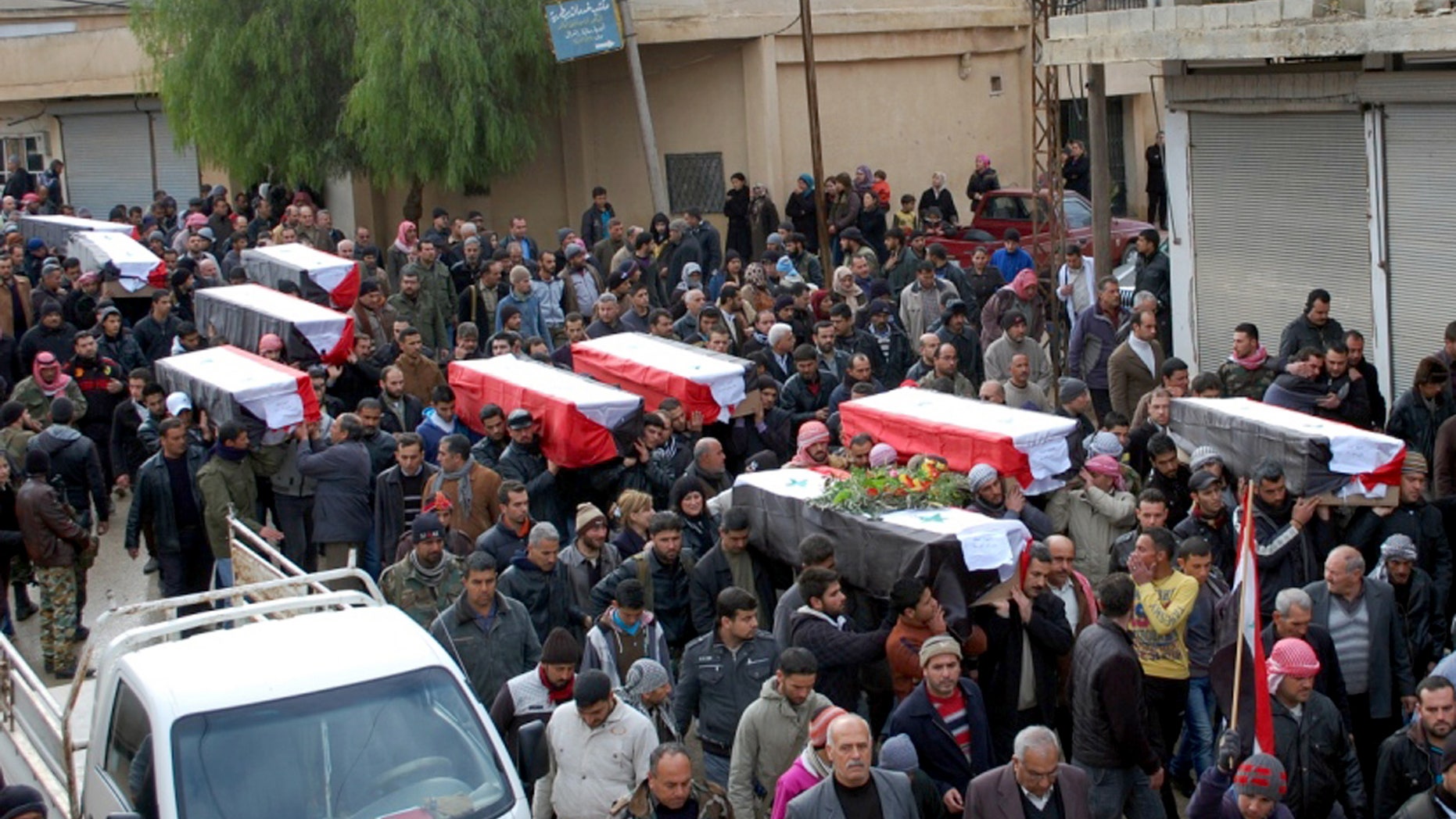 In this photo released by the Syrian official news agency SANA, Syrian citizens carry the coffins wrapped by Syrian flags for the victims who were killed Thursday by a car bomb, during their funeral processions, at al-Kaffat village in the central Hama province, Syria, Friday, Jan. 10, 2014. Rebel-on-rebel fighting between an al-Qaida-linked group and an array of more moderate and ultraconservative Islamists has killed nearly 500 people over the past week in northern Syria, an activist group said Friday, in the most serious bout of violence among opponents of President Bashar Assad since the civil war began. (AP Photo/SANA)