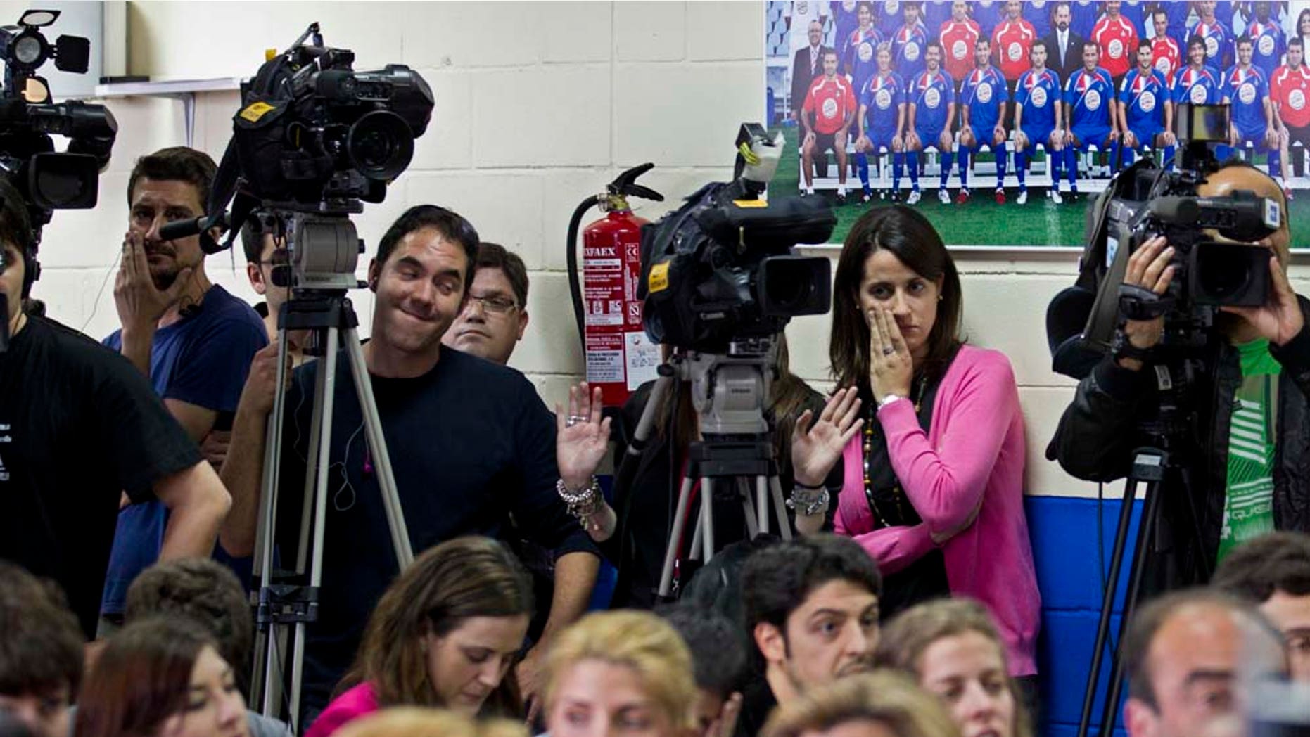 Journalists work next to an old Getafe team poster during a press conference by the president of Getafe soccer club Angel Torres, unseen, in Getafe, Spain Monday April 25, 2011. Torres announced that a Dubai business has bought the club. (AP Photo/Paul White)