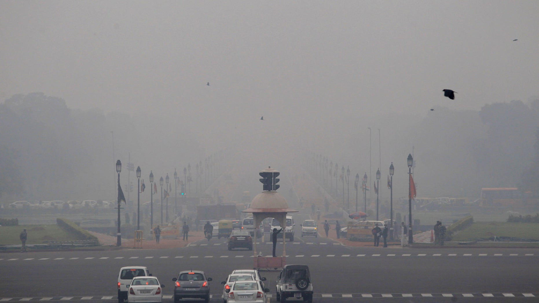 Smog and fog envelop the Rajpath, the ceremonial boulevard, behind, as a police man, center, controls traffic in the morning in New Delhi, India, Wednesday, Feb. 5, 2014. On bad days in India’s congested capital, the air is so murky it slows traffic to a crawl because visibility is so poor. Conversations are punctuated with rasping coughs. Weak bands of sunlight filter through a grainy sky. (AP Photo/Tsering Topgyal)
