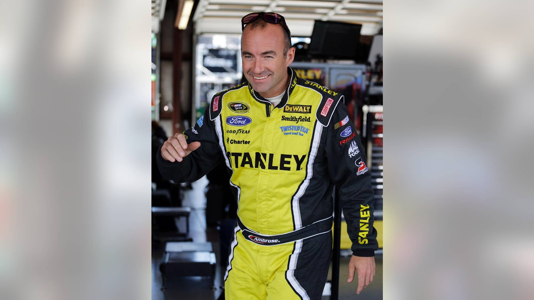 NASCAR driver Marcos Ambrose (9) smiles as he leaves his garage during final practice for the NASCAR Sprint Cup Series auto race at Chicagoland Speedway in Joliet, Ill., Saturday, Sept. 13, 2014. (AP Photo/Nam Y. Huh)