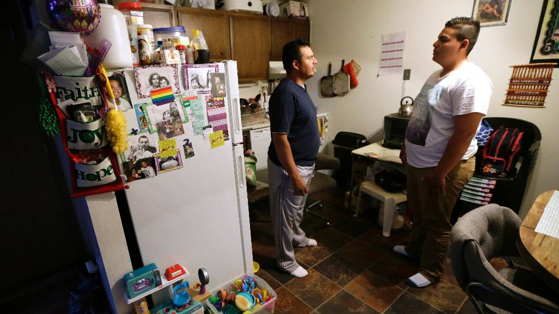 Alejandro Lopez, of Des Moines, Iowa, left, talks with his son Jonathan about his application for asylum, Tuesday, May 10, 2016, in Clive, Iowa. For immigrant children seeking asylum in the U.S., where they apply seems to make a world of difference. (AP Photo/Charlie Neibergall)