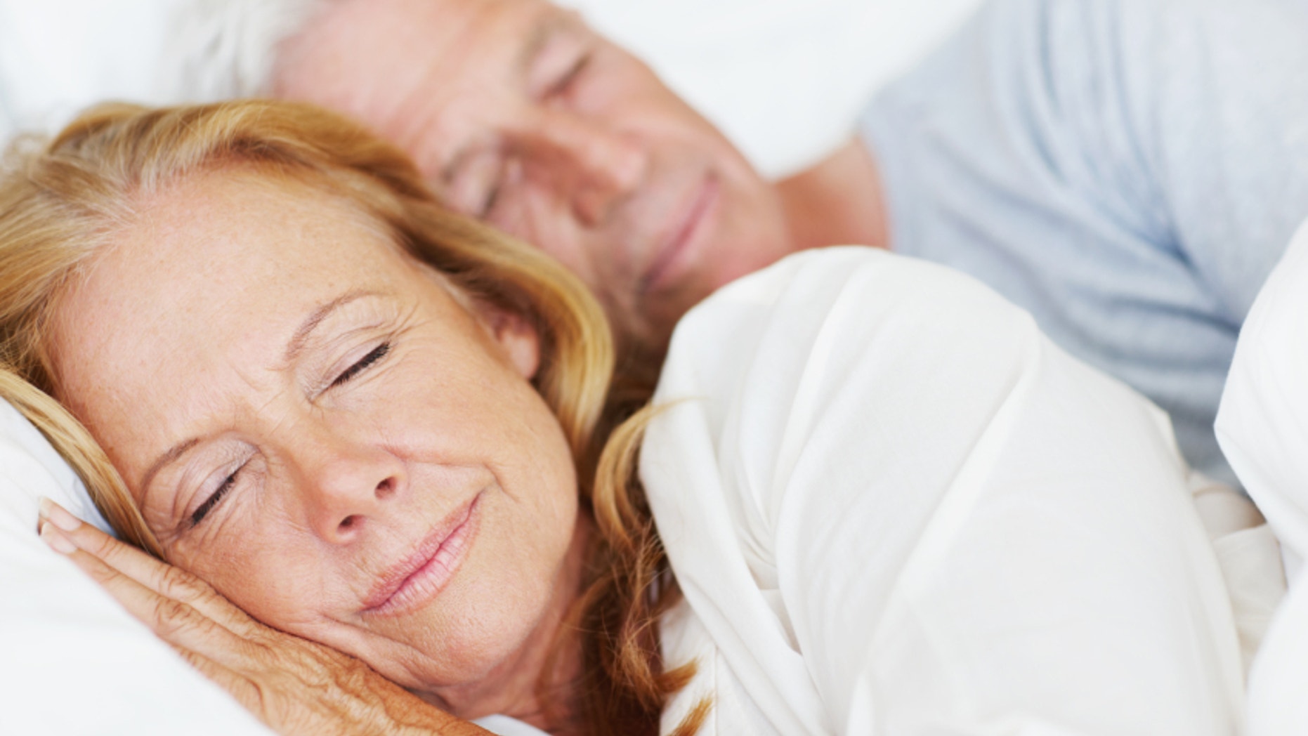 Attractive senior couple lying in bed together and sleeping