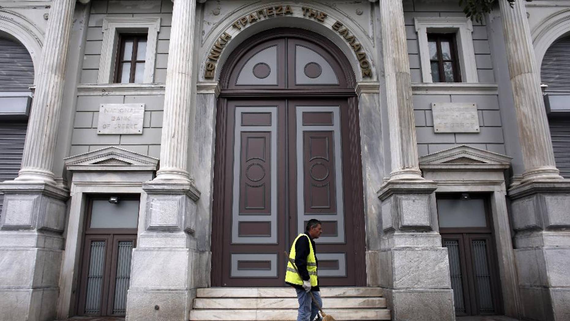 A cleaning worker walks past the headquarters of National Bank of Greece, in Athens, on Sunday, Oct. 26, 2014. The European Central Bank says 13 of Europe's 130 biggest banks have flunked an in-depth review of their finances and must increase their capital buffers against losses by 10 billion euros ($12.5 billion). The ECB said 25 banks in all were found to need stronger buffers — but that 12 have already made up their shortfall. The remaining 13 now have two weeks to tell the ECB how they plan to increase their capital buffers. (AP Photo/Kostas Tsironis)