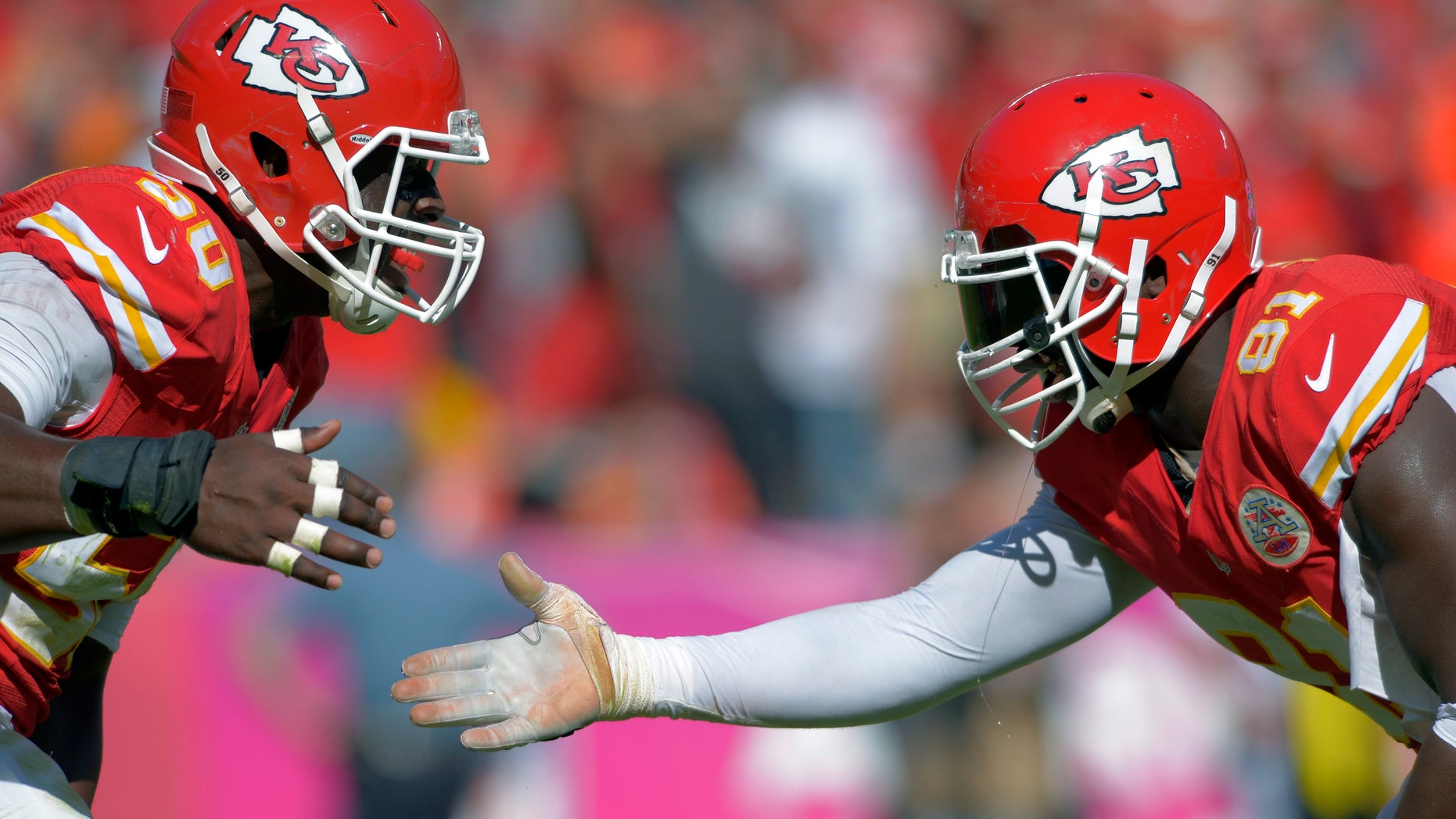 ADVANCE FOR WEEKEND EDITIONS, OCT. 26-27 - FILE - In this Oct. 13, 2013, file photo, Kansas City Chiefs outside linebackers Justin Houston (50) and Tamba Hali (91) celebrate a sack of Oakland Raiders quarterback Terrelle Pryor during an NFL football game in Kansas City, Mo. Both of them get to the quarterback with such frequency that opposing coaches have to pick their poison. They're the two biggest playmakers on the Chiefs' defense. In some ways, you could call them the H-factor. (AP Photo/Reed Hoffmann, File)