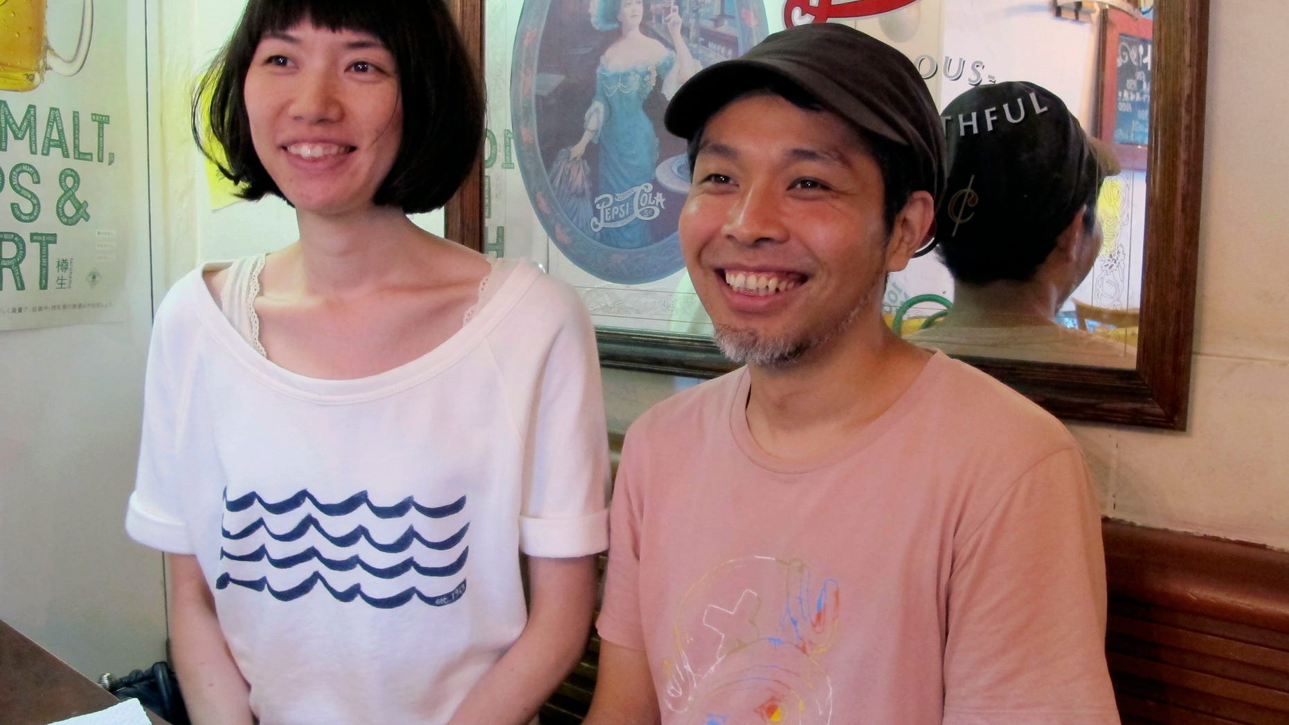 In this Friday, July 12, 2013, photo, Teruyuki Kawabata, right, 36, and his wife Haruna, 32, smile during an interview in Tokyo. Both Teruyuki and Haruna were children when Japan’s bubble economy burst more than two decades ago. Now, they have little interest in the stock market. (AP Photo/Yuri Kageyama)