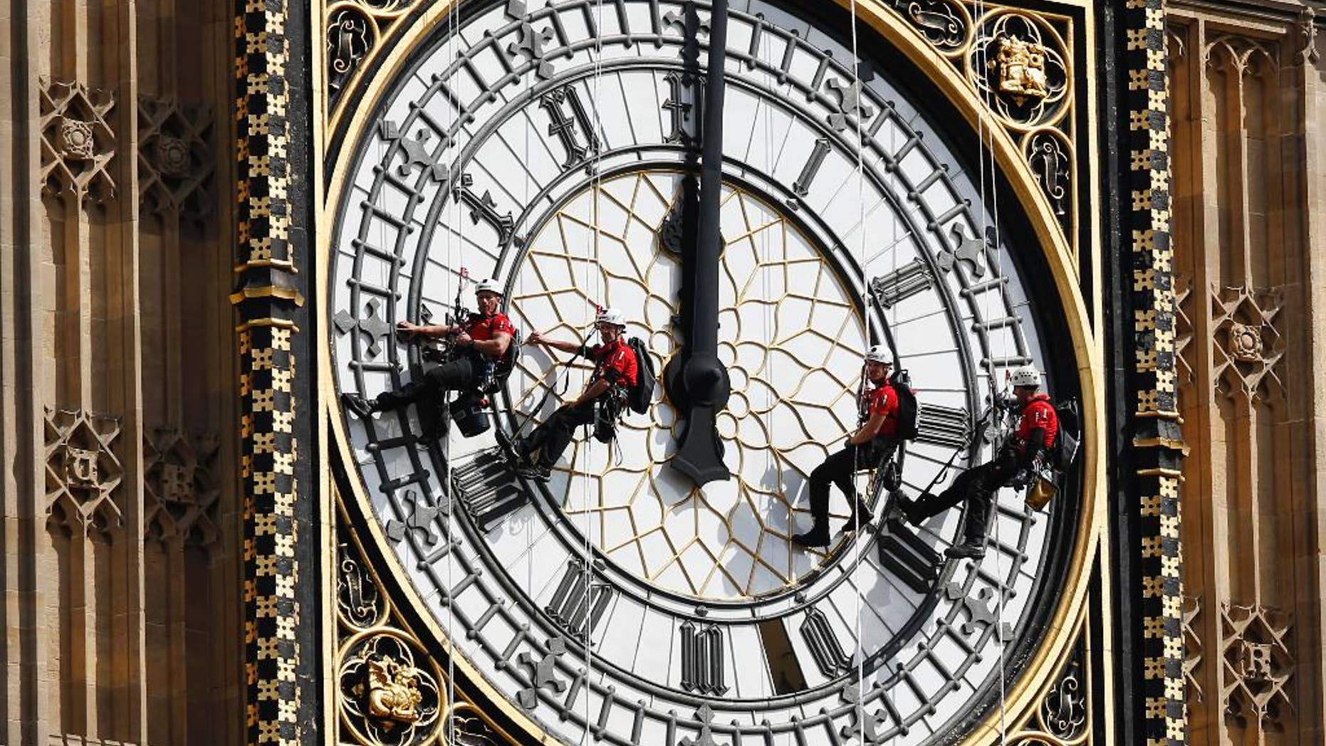FILE- In this file photo dated Monday, Aug. 18, 2014, workers abseil outside the clock face as they clean Big Ben's clock tower of the Houses of Parliament in London. According to reports published Sunday Oct. 18, 2015, the chimes of Big Ben may fall silent for many months as urgent repairs are carried out to the clock and the tower, which must begin as soon as possible.(AP Photo/Sang Tan, FILE)