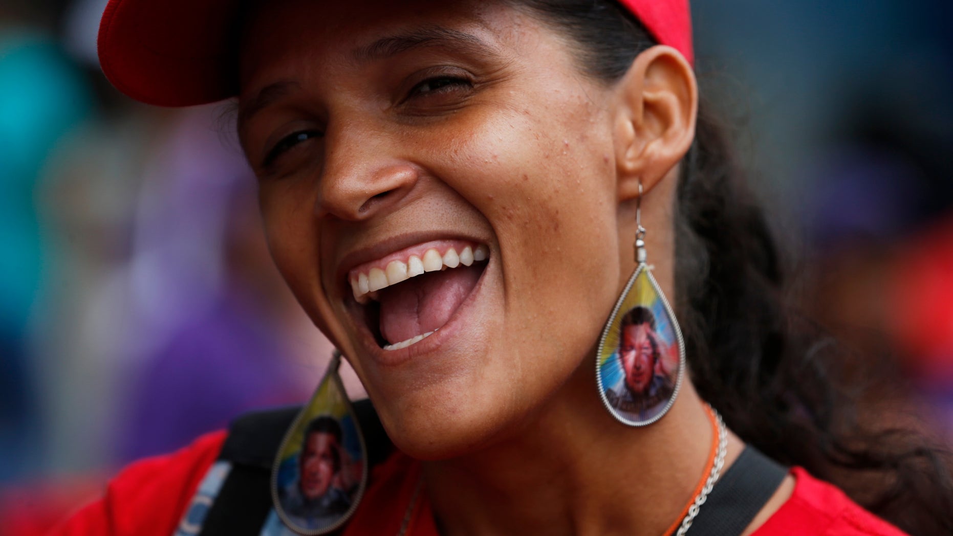A woman wearing earrings designed with an image of the late President Hugo Chavez, smiles during a pro-government rally in Caracas, Venezuela, Saturday, Feb. 22, 2014. Venezuelans on both sides of the nation's political divide took to the streets on Saturday after nearly two weeks of mass protests that have Venezuelan President Nicolas Maduro scrambling to reassert his leadership. (AP Photo/Fernando Llano)