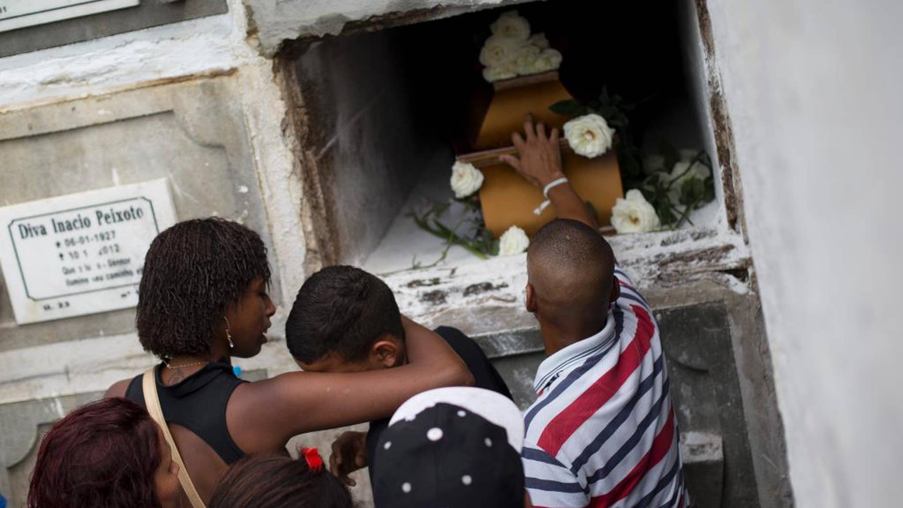 FILE - In this Sept. 30, 2015 file photo, relatives and friends of Eduardo Felipe Santos Victor, a teenager who was shot dead in the Morro da Providencia slum, mourn during his funeral in Rio de Janeiro, Brazil. Five Brazilian police officers were taken into custody for allegedly altering a crime scene by placing a gun in the hand of the seventeen-year-old, after they allegedly killed him during a shootout in a Rio de Janeiro. As he lay dying in a pool of blood, a slum resident shot video of one of the officers firing a handgun into the air and then putting the gun in Victor's hand. (AP Photo/Silvia Izquierdo, File)
