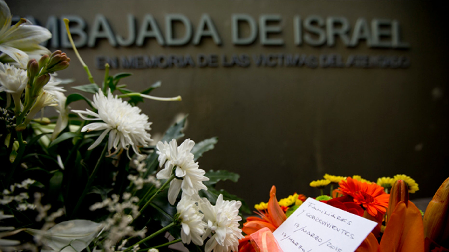 A piece of paper reading in Spanish "Relatives and survivors, March 17, 2015, March 17, 1992" is placed on floral arrangements that sit where the Israeli Embassy used to be, during an act to commemorate the 23rd anniversary of the bomb attack that destroyed the Israeli Embassy building killing 22 people in Buenos Aires, Argentina, Tuesday, March 17, 2015. (AP Photo/Natacha Pisarenko)