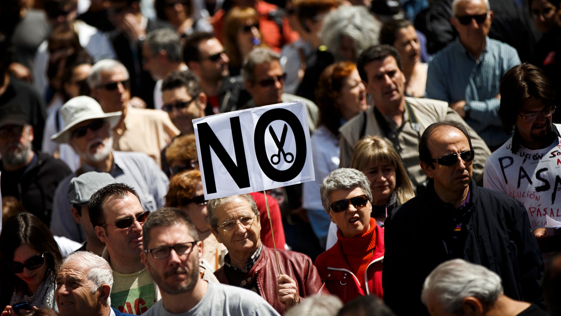 A protestor walks holding a banner reading 'No' during a demonstration against regional government imposed austerity plans to restructure and part privatize the health care sector in Madrid, Sunday, April 21, 2013. Madrid proposes selling off the management of six of 20 public hospitals and 27 of 268 health centers. Spain's regions are struggling with a combined debt of $190 billion (145 billion euro) as the country's economy contracts into a double-dip recession triggered by a 2008 real estate crash. (AP Photo/Daniel Ochoa de Olza)
