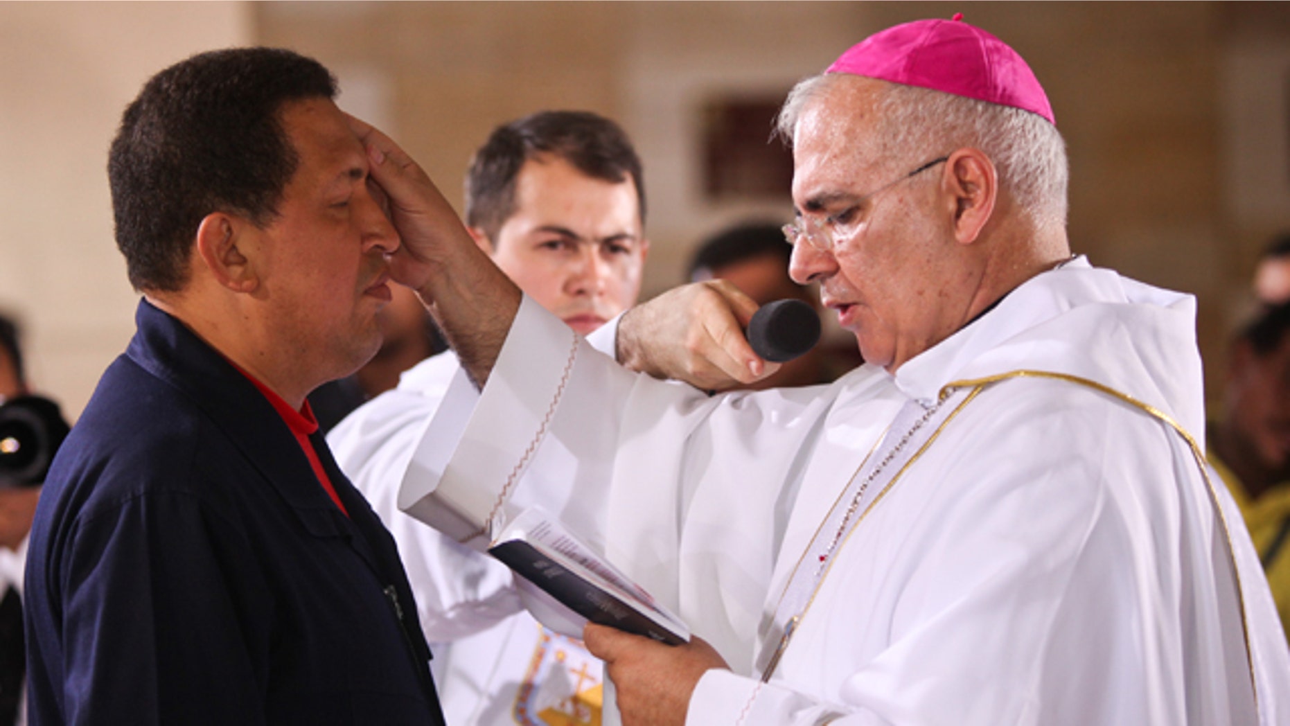 July 12: In this photo provided by Miraflores presidential press office, priest Mario Moronta, right, makes a cross sign on Venezuela's President Hugo Chavez's forehead during a mass for Chavez's recovery in Caracas, Venezuela. Chavez underwent surgery in Cuba last June 20 to remove a tumor from his pelvic region. (AP Photo/Miraflores Presidential Office)