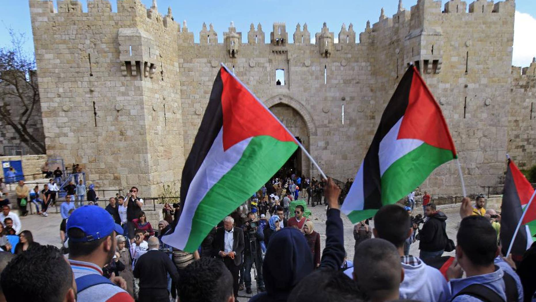 Palestinians carry national flags during a protest marking Land Day in front of the Damascus Gate in Jerusalem's Old City, Monday, March 30, 2015. Land Day commemorates riots on March 30, 1976, when six people were killed during a protest by Israeli Arabs whose property was annexed in northern Israel to expand Jewish communities. (AP Photo/Mahmoud Illean)