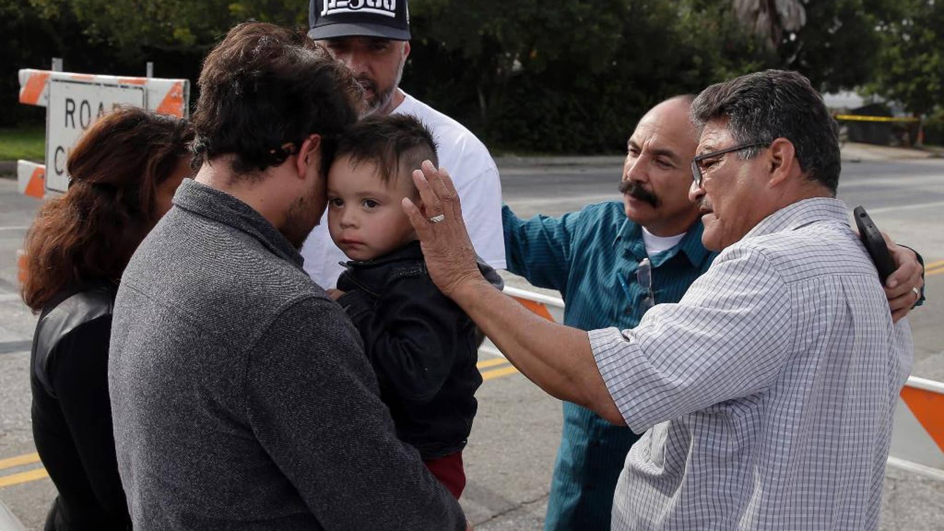 A group of local church members pray for residents who live in the neighborhood where Wednesday's police shootout with suspects took place, Thursday, Dec. 3, 2015, in San Bernardino, Calif. Multiple attackers opened fire on a banquet at a social services center for the disabled in San Bernardino on Wednesday, killing multiple people and sending police on a manhunt for suspects. (AP Photo/Chris Carlson)