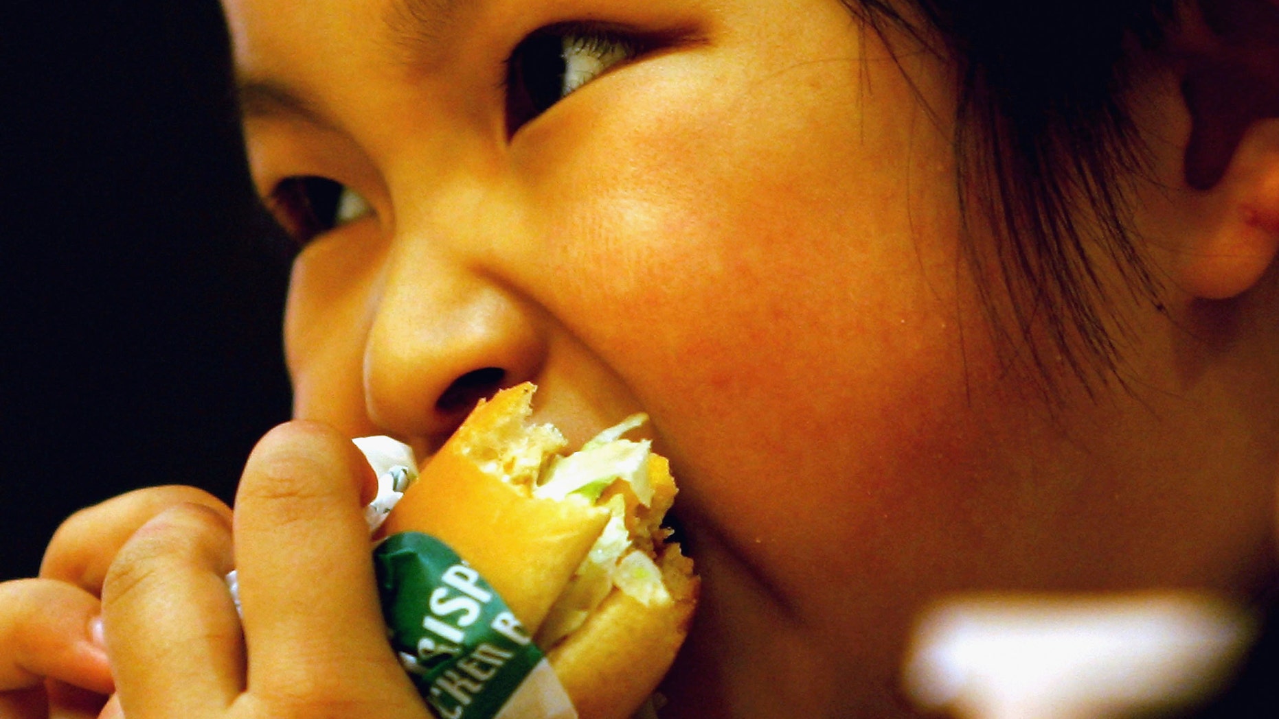 BEIJING - MAY 31: A Chinese girl eats a hamburger at an American fast food chain for an activity to mark International Children's Day with her parents on May 31, 2005 in Beijing, China. The International Children's Day falls on June 1 every year in the mainland. (Photo by Guang Niu/Getty Images)