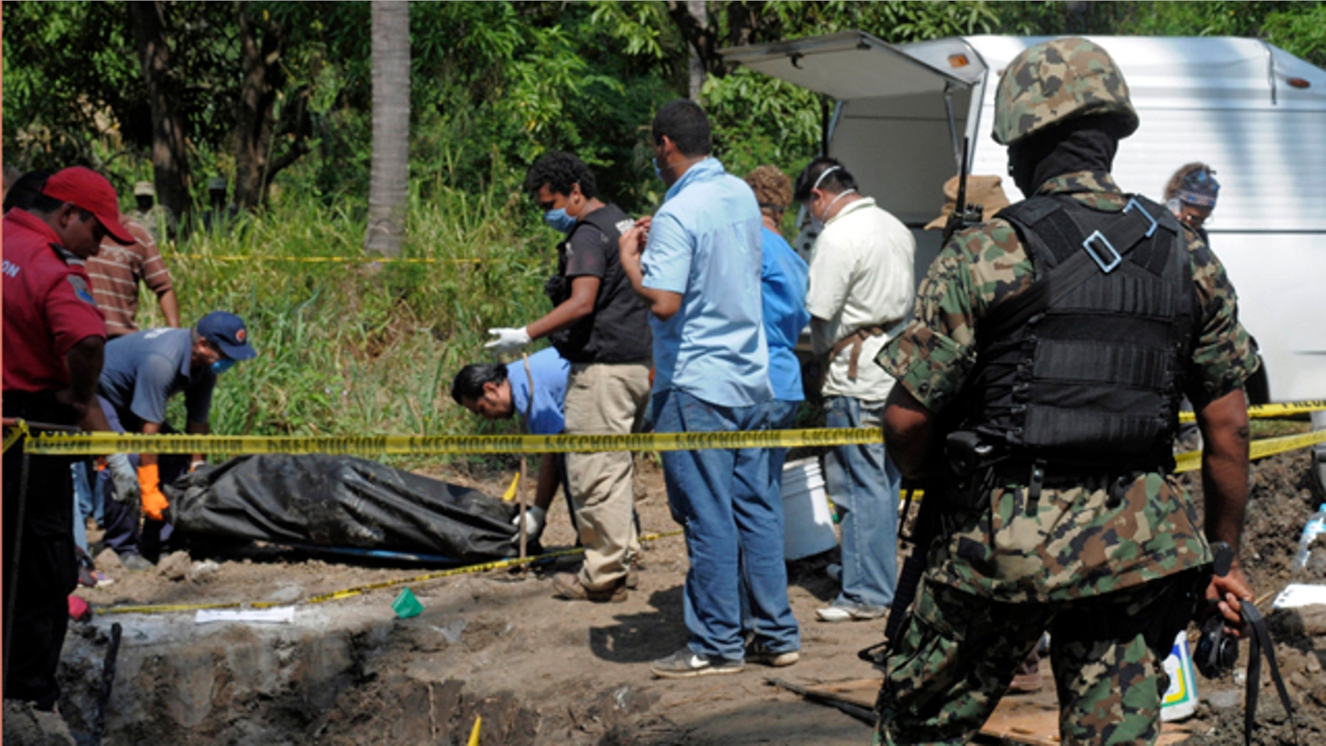Nov. 3, 2010: A Mexican Navy soldier watch as forensic workers remove a body which was buried at a field in the town of Tuncingo, southern Mexico.