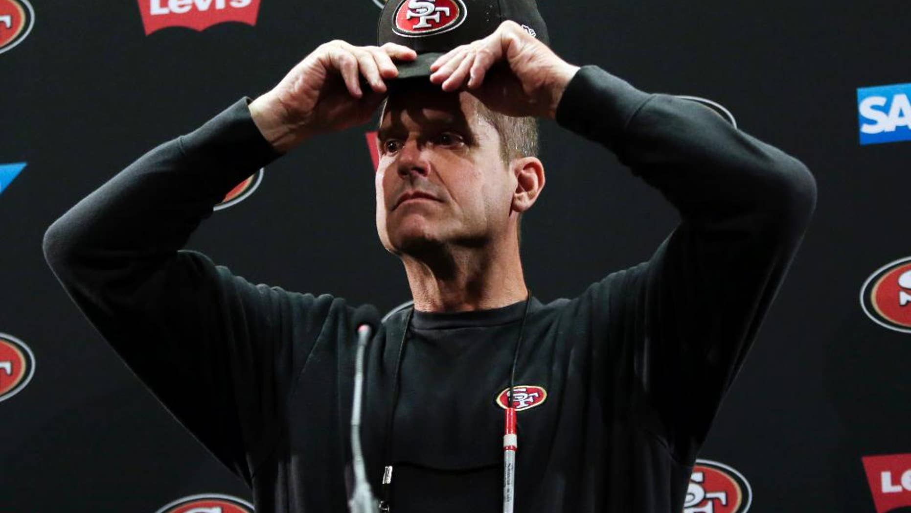 San Francisco 49ers head coach Jim Harbaugh adjust his cap as he answers questions from the media during an NFL football training camp on Thursday, July 24, 2014, in Santa Clara, Calif. (AP Photo)
