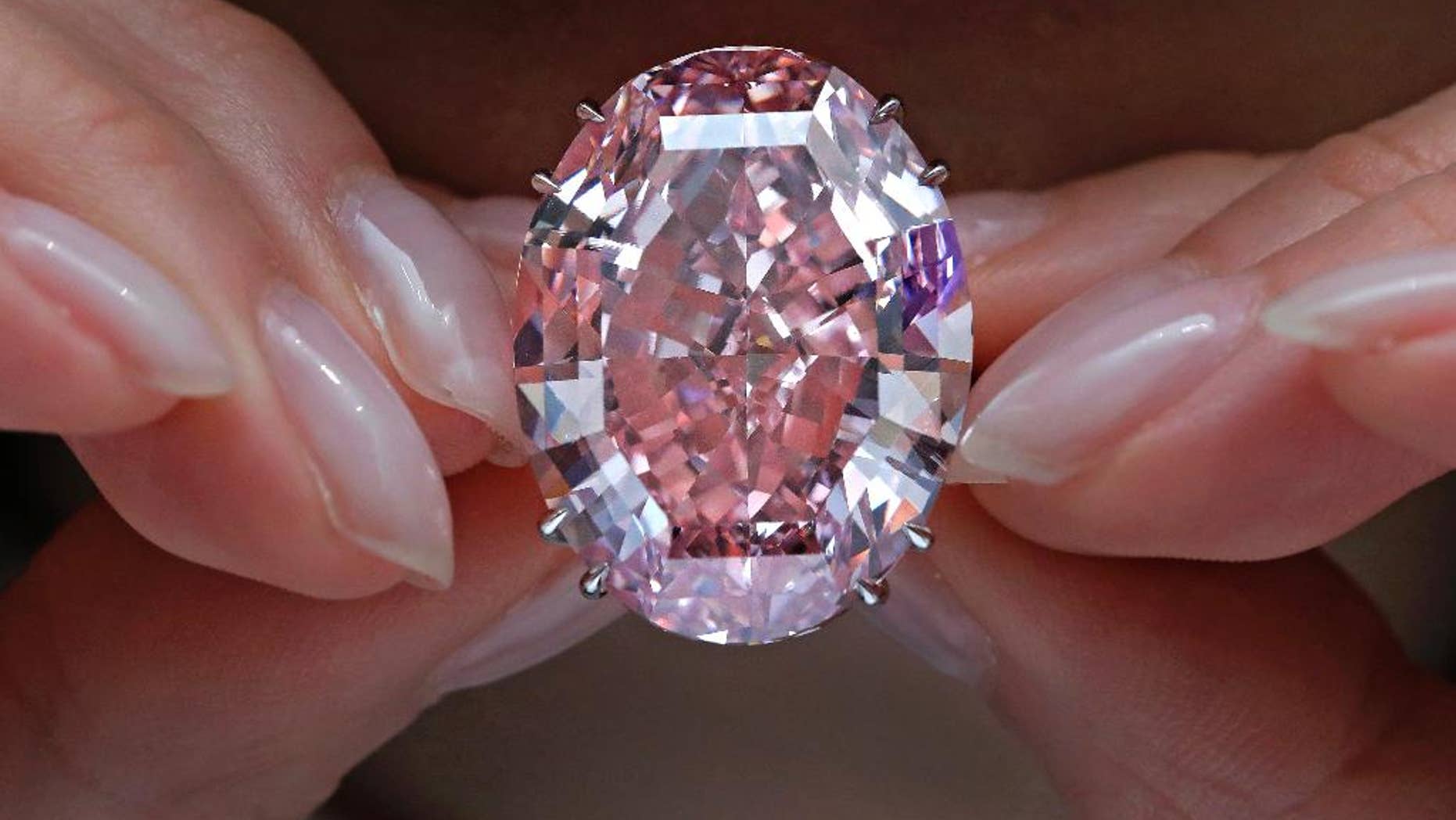 FILE - In this Wednesday, March 29, 2017, file photo, the "Pink Star" diamond, the most valuable cut diamond ever offered at auction, is displayed by a model at a Sotheby's auction room in Hong Kong. The stunning 59.6 carat diamond has sold for HK$553 million or US$71.2 million at a Sotheby's auction in Hong Kong, setting a record for any diamond or jewel. It's Also the highest price for any work ever sold at auction in Asia. (AP Photo/Vincent Yu, File)