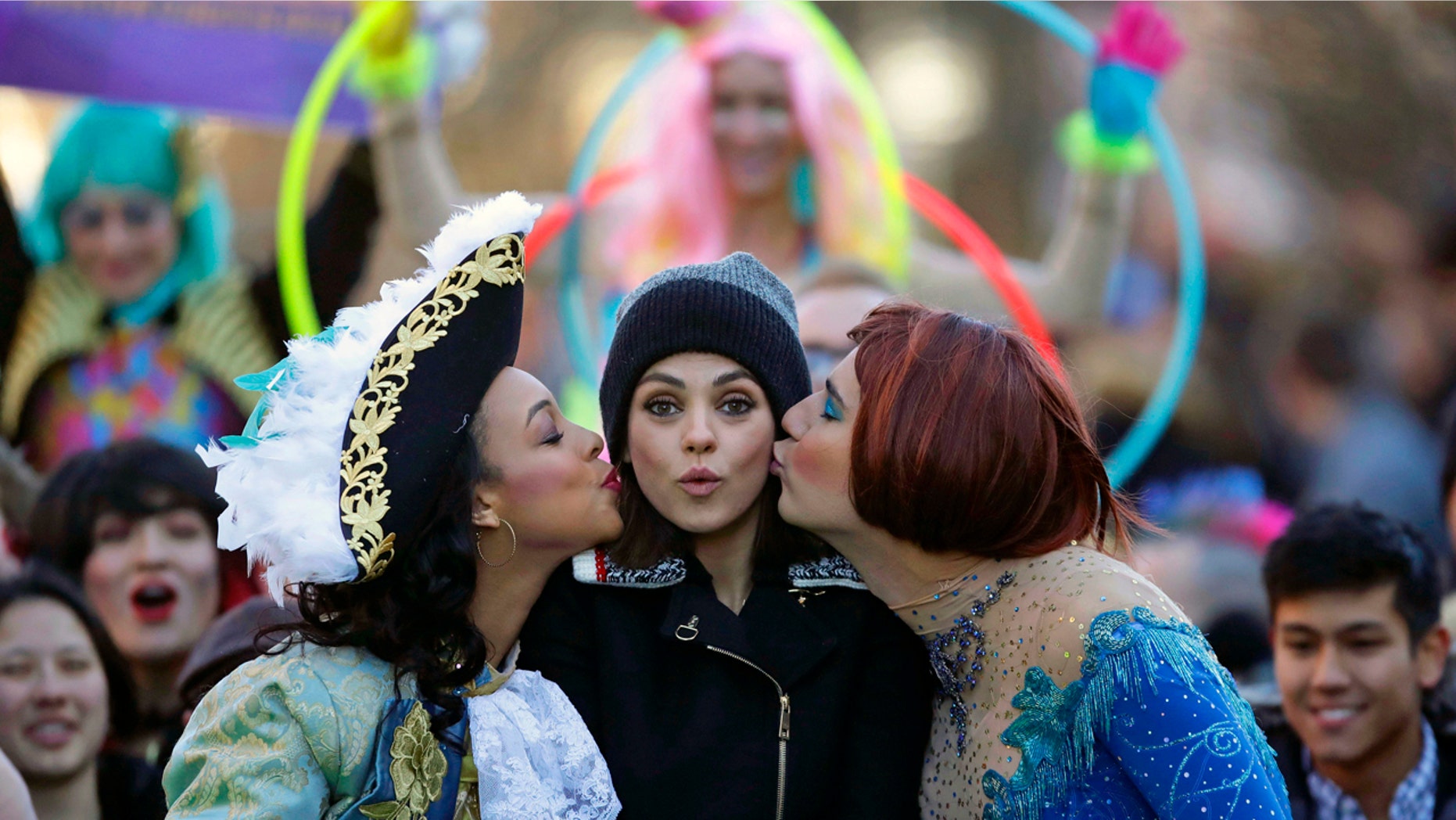 Actress Mia Kunis, center, is kissed by Amira Weeks, left, and Jacques Berguig during a parade for Kunis in Cambridge, Thursday, Jan. 25, 2018. Kunis was honored as "Woman of the Year" by the Hasty Pudding Theatricals at Harvard University. (AP Photo/Charles Krupa)