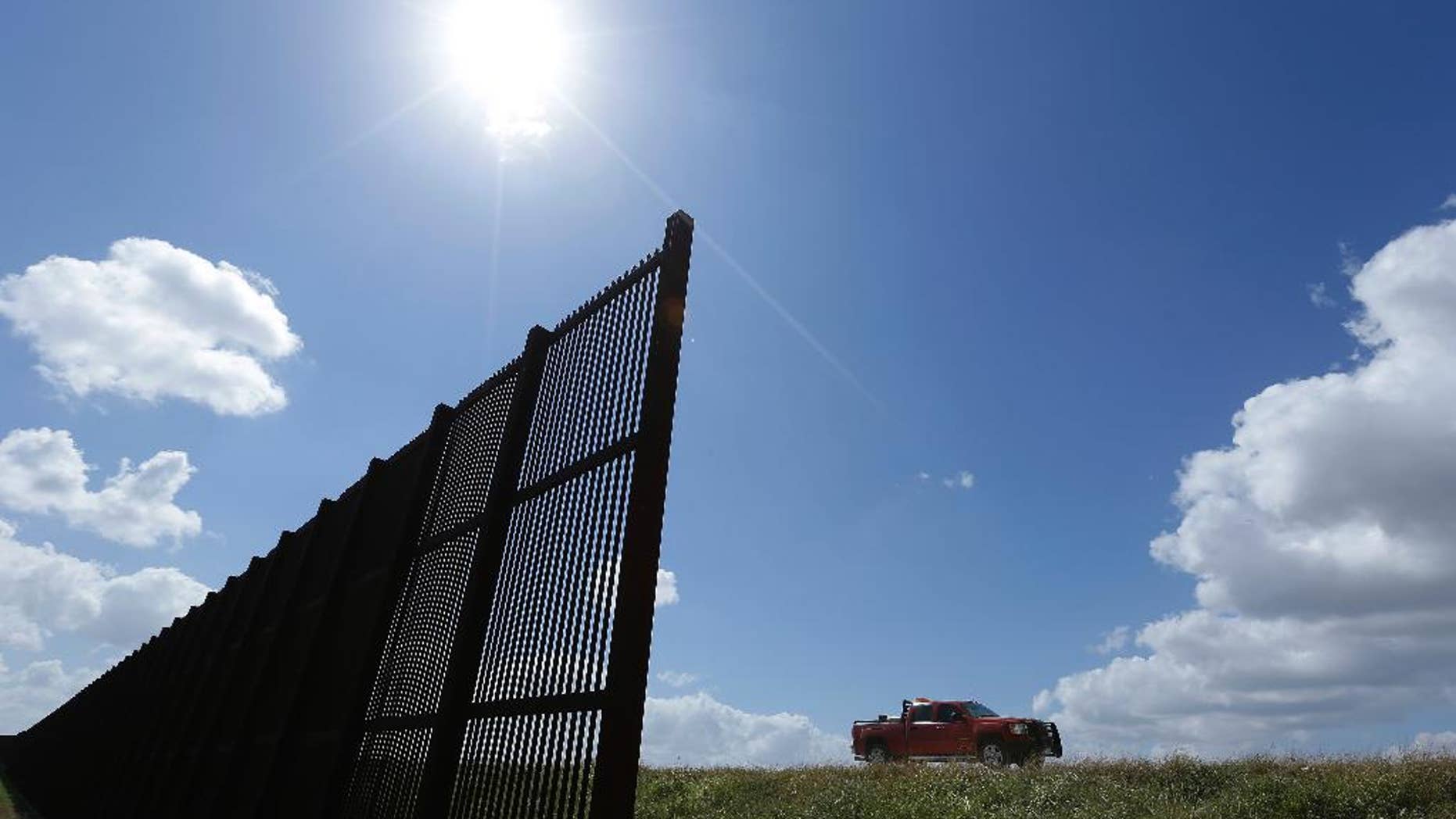 FILE - In this Sept. 6, 2012, file photo, cotton farmer Teofilo "Junior" Flores drives his truck along the U.S.-Mexico border fence that passes through his property in Brownsville, Texas. President Donald Trump’s vow to accelerate construction of a “contiguous, physical wall” along the Mexican border is slamming into a Washington reality _ who’s going to pay for it and how? (AP Photo/Eric Gay, File)