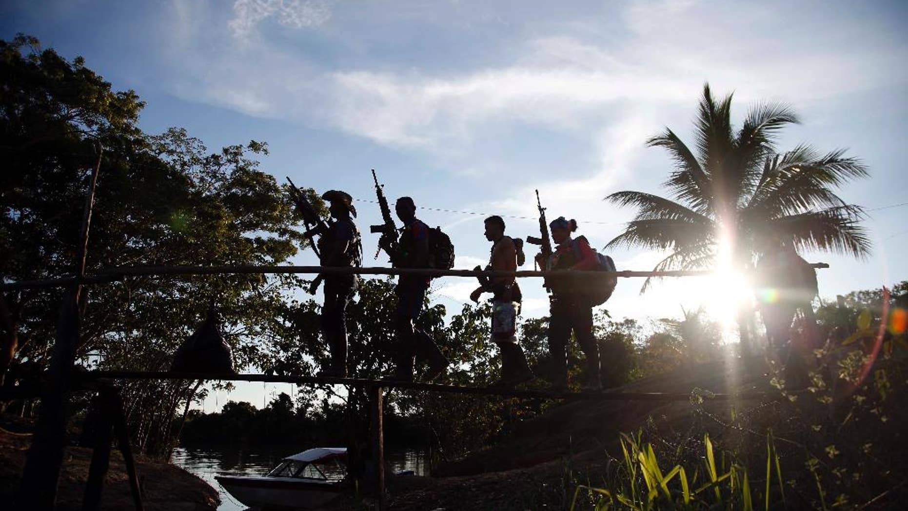 In this Aug. 12, 2016 photo, rebels of the 48th Front of the Revolutionary Armed Forces of Colombia walk on a makeshift footbridge in the southern jungles of Putumayo, Colombia. With the peace accords about to signed between the FARC and the governemt, gone are the days when they had to change camp every few days for fear of being stunned in their sleep by bombs falling from the skies. (AP Photo/Fernando Vergara)