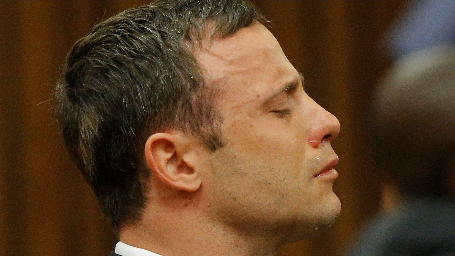 Oscar Pistorius reacts in the dock in Pretoria, South Africa, Thursday Sept. 11, 2014 as Judge Thokozile Masipa reads notes as she delivers her verdict in Pistorius' murder trial. The South African judge in Oscar Pistoriusâ murder trial said Thursday that prosecutors have not proved beyond a reasonable doubt that the double-amputee Olympic athlete is guilty of premeditated murder. (AP Photo/Kim Ludbrook, Pool)