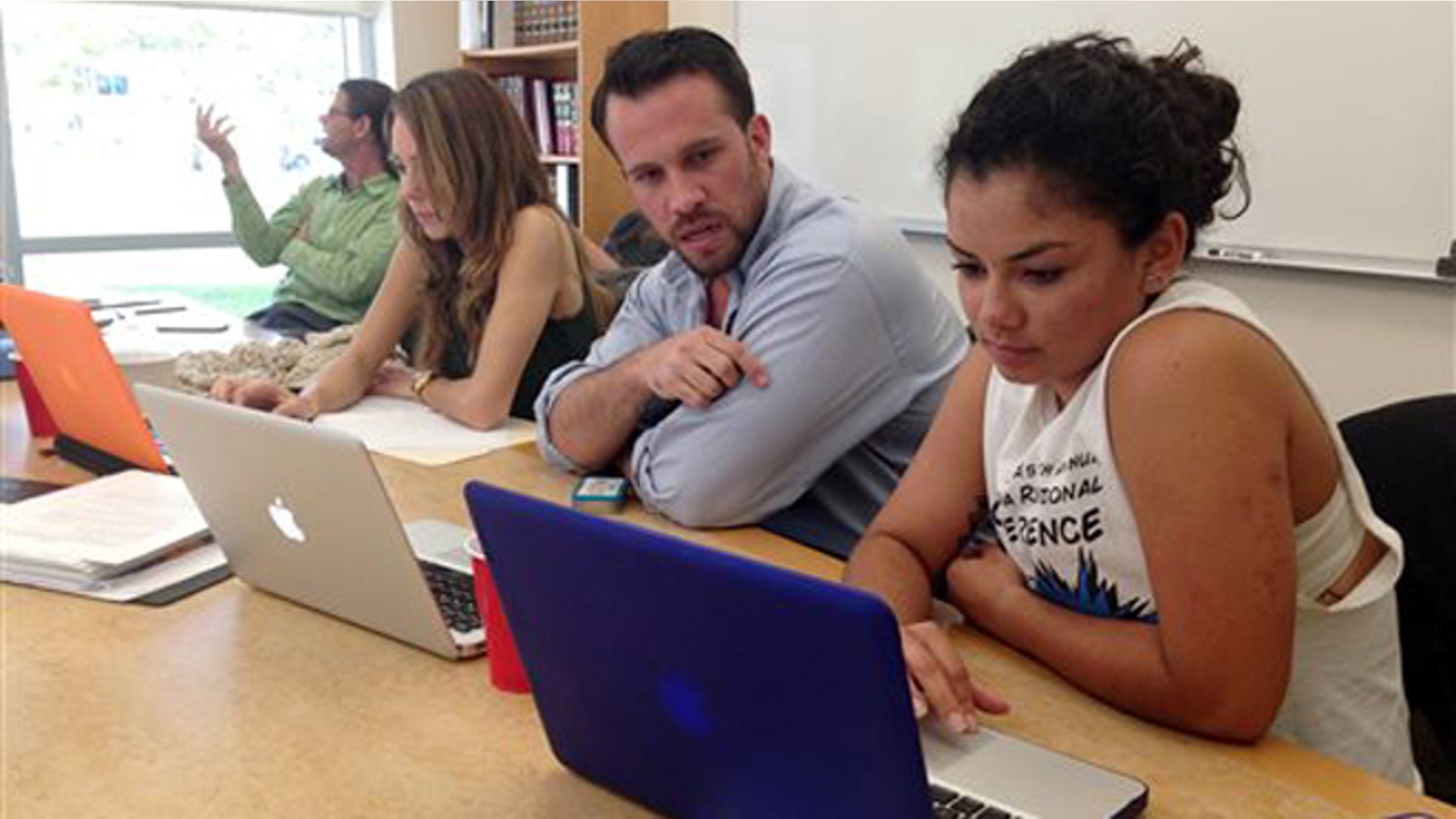 CORRECTS NAMES AND AGES Anthony Rouzier helps Valentina Adarraga, 20, sign up for health insurance under the Affordable Care Act in Miami, Friday, March 21, 2014. Rouzier took five hours of training to be become a certified application counselor to assist those that want to enroll in the federal health care program.