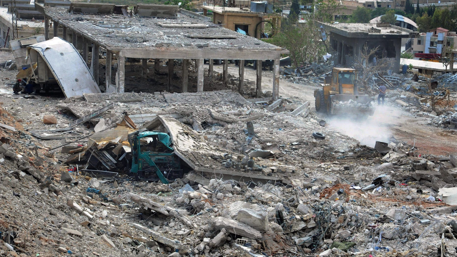FILE - In this Sunday, May 5, 2013 file photo provided by the Syrian official news agency SANA, workers clear the rubble of buildings destroyed by an Israeli airstrike in Damascus, Syria. The attack targeted a shipment of highly accurate, Iranian-made guided missiles believed to be on their way to Lebanon's Hezbollah militant group, officials and activists said. The Syrian regime has enlisted a Damascus-based Palestinian militant group to threaten retaliation for the airstrikes. The relatively muted response to Israel's breach of Syrian sovereignty highlights President Bashar Assad's limited options as his regime battles for survival. (AP Photo/SANA, File)