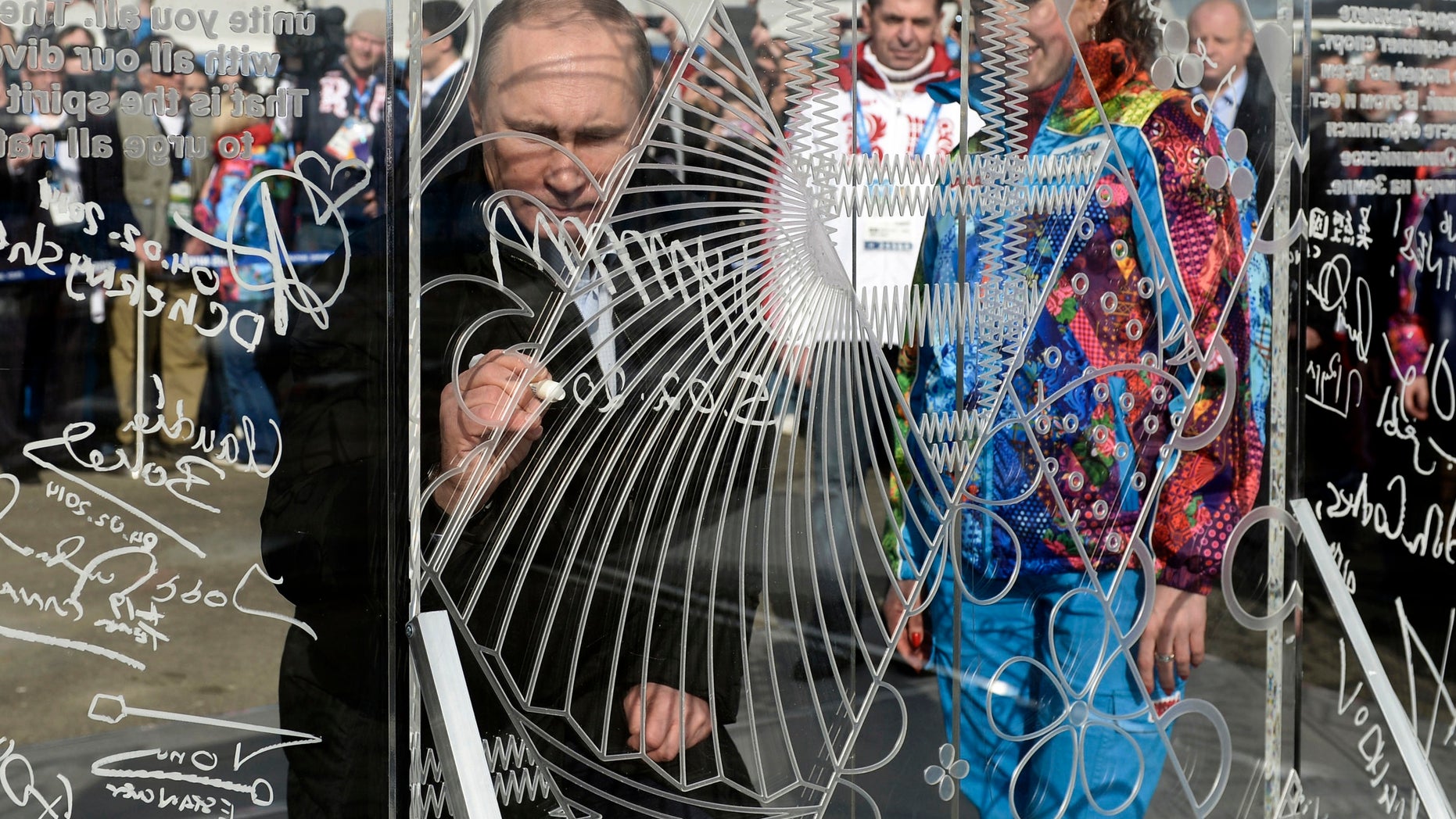 Russian President Vladimir Putin signs a wall while visiting the Coastal Cluster Olympic Village ahead of the Sochi 2014 Winter Olympics on Wednesday, Feb. 5, 2014, in Sochi, Russia. (AP Photo/RIA-Novosti, Alexei Nikolsky, Presidential Press Service)