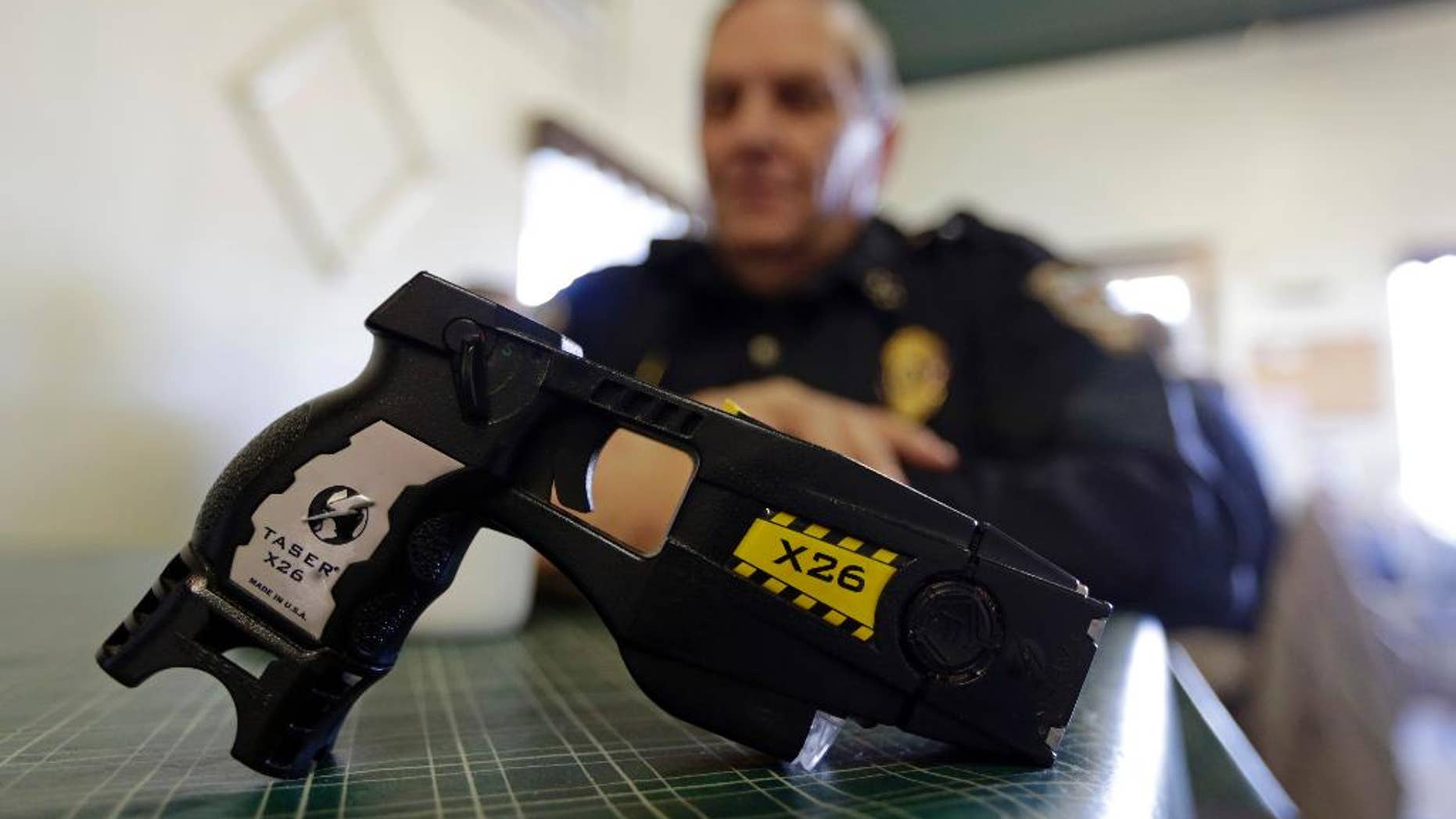 FILE - In this Nov. 14, 2013, file photo, a Taser X26 sits on a table in Knightstown, Ind. In the recent shootings of unarmed black men in a San Diego suburb and in Tulsa, Oklahoma, the police officers who fired the fatal shots were accompanied by officers who simultaneously drew their stun guns. Civil rights advocates say the different response by officers facing the same suspect and the same apparent threat illustrates a breakdown in police training and communication and shows that some officers are too quick to turn to deadly force. (AP Photo/Michael Conroy, File)
