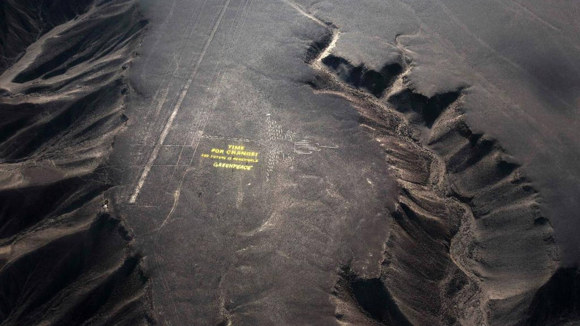 Greenpeace activists stand next to massive letters delivering the message "Time for Change: The Future is Renewable," next to the hummingbird geoglyph in Nazca in Peru, Monday, Dec. 8, 2014. Greenpeace activists from Brazil, Argentina, Chile, Spain, Germany, Italy and Austria displayed the message, which can be viewed from the sky, during the climate talks in Peru, to honor the Nazca people, whose ancient geoglyphs are one of the country's cultural landmarks. (AP Photo/Rodrigo Abd)
