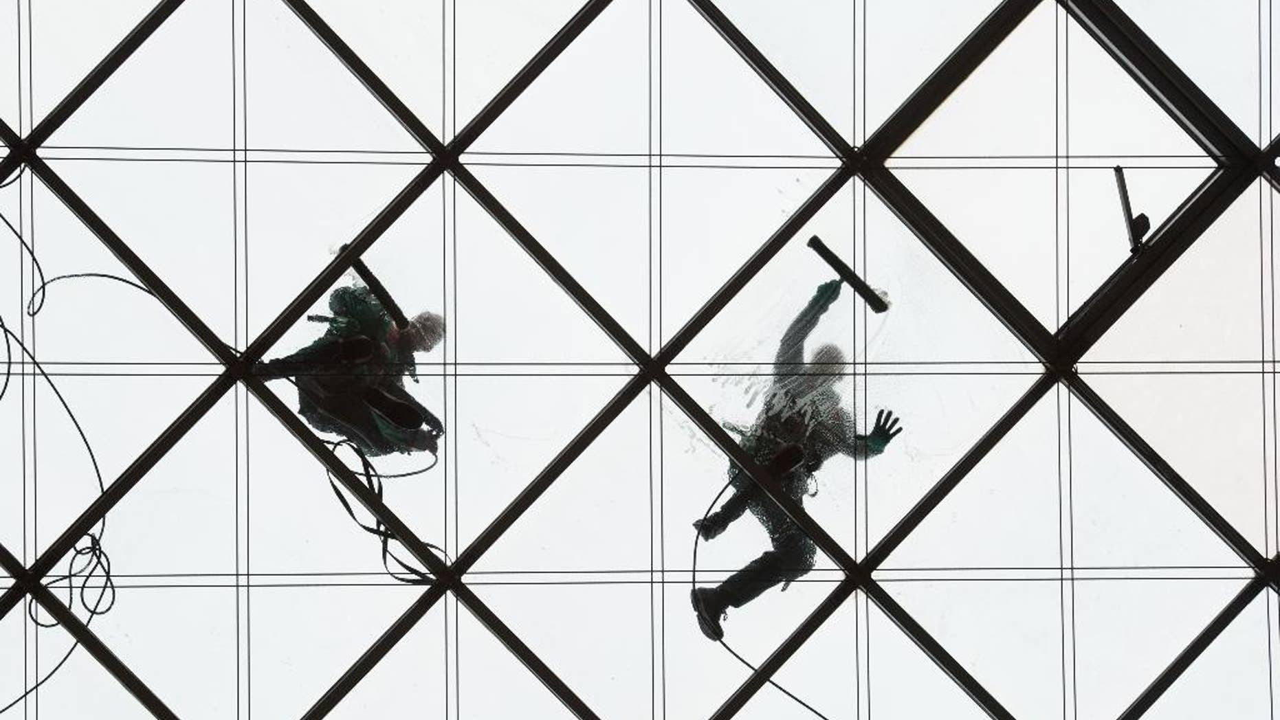 Two window cleaners work on the 27-meters-high glass ceiling of a building in Dresden, Germany, Wednesday, March 30, 2016. (Sebastian Kahnert/dpa via AP)
