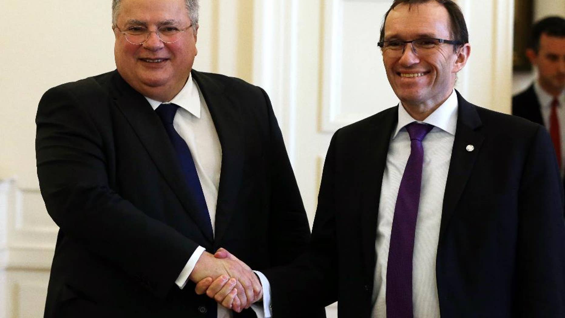Greek Minister for Foreign Affairs Nikos Kotzias, left, shakes hands with the U.N. Special Advisor of the Secretary-General Espen Barth Eide before their meeting to discuss the progress of Cyprus Peace Talks in Athens, Friday, Feb. 3, 2017. The rival leaders of ethnically split Cyprus have asked the United Nations to prepare for a follow-up summit in early March that will aim to clinch a breakthrough on the difficult issue of how security will be handled after the island is reunified, a U.N. envoy said Wednesday. (AP Photo/Thanassis Stavrakis)