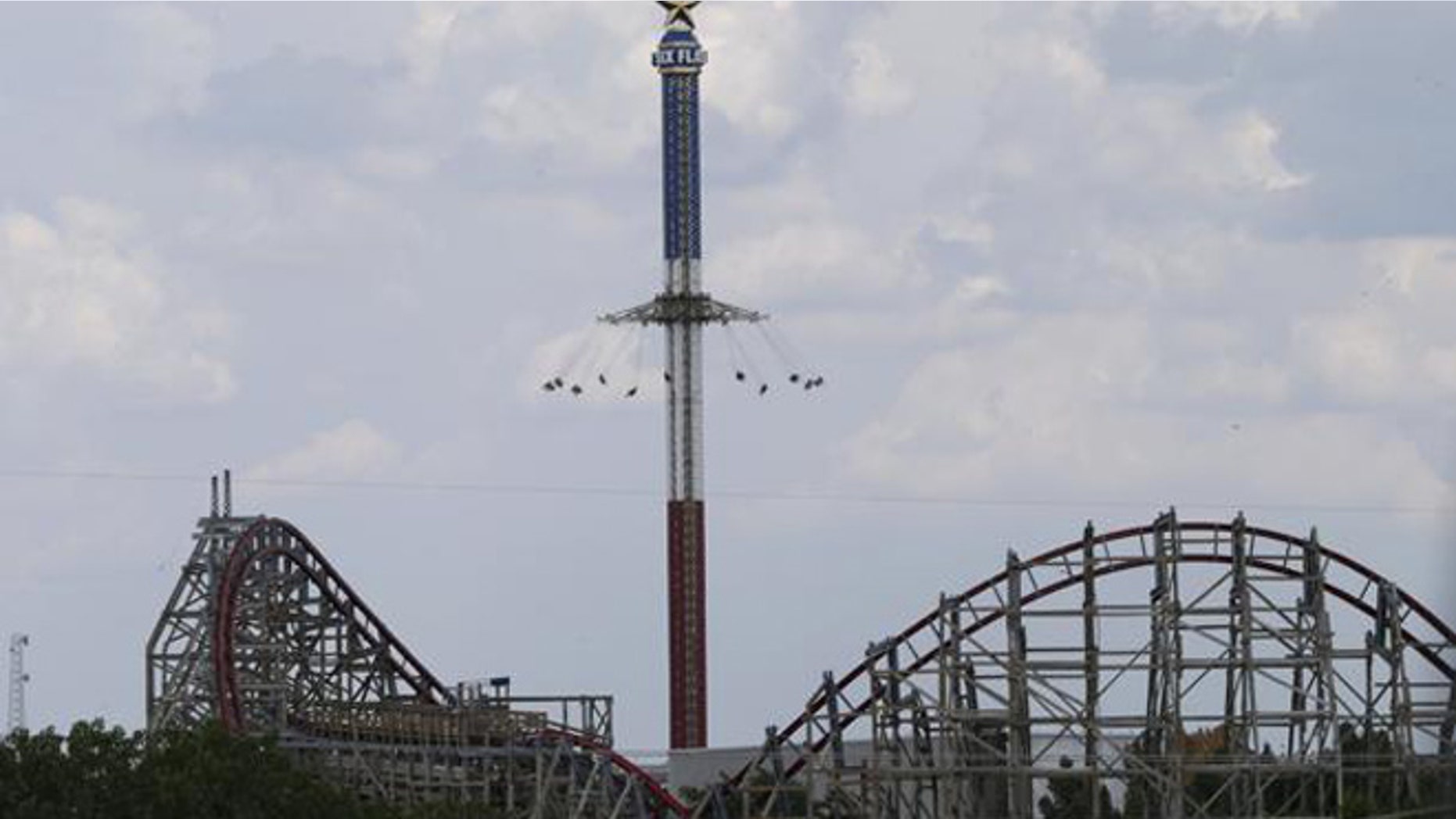 The Texas Giant roller coaster ride sits idle in the foreground as people take in another ride a the Six Flags Over Texas park on Saturday, July 20, in Arlington, Texas.