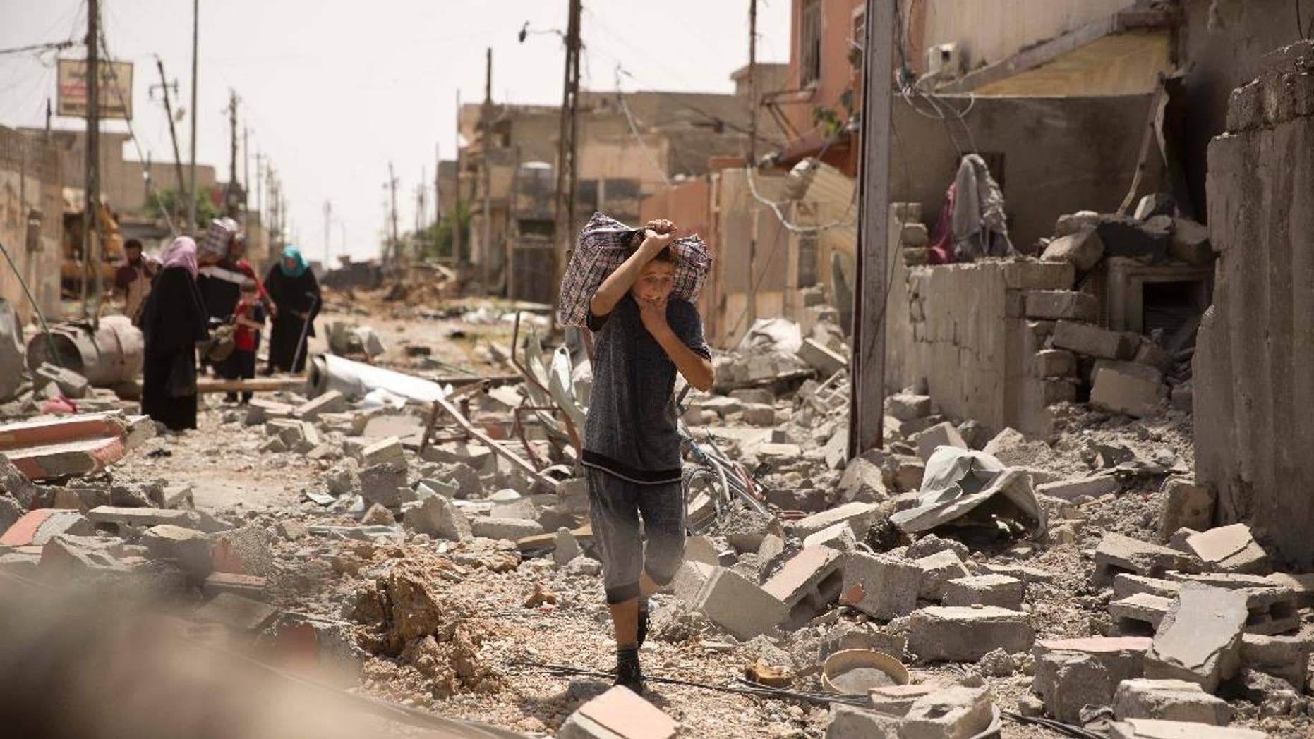 An Iraqi boy carries heavy belongings through rubble as he flees fighting between Iraqi special forces and Islamic State militants, in western Mosul, Iraq, Monday, May 15, 2017. (AP Photo/Maya Alleruzzo)