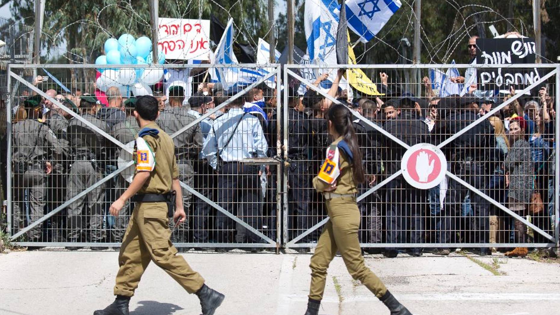 FILE - In this Tuesday, March 29, 2016 file photo, Israeli right wing protesters wave flags outside of Castina Military Court near the southern Israeli city of Ashkelon. Israel’s military justice system is in the spotlight as it investigates an Israeli soldier caught on tape shooting to death a subdued Palestinian attacker, a case that has gripped and polarized the nation. While the military has stressed the independence of its courts, critics say the system’s poor track record for punishing errant soldiers is perpetuating a culture of impunity that allows allegedly improper conduct to recur. (AP Photo/Ariel Schalit, File)