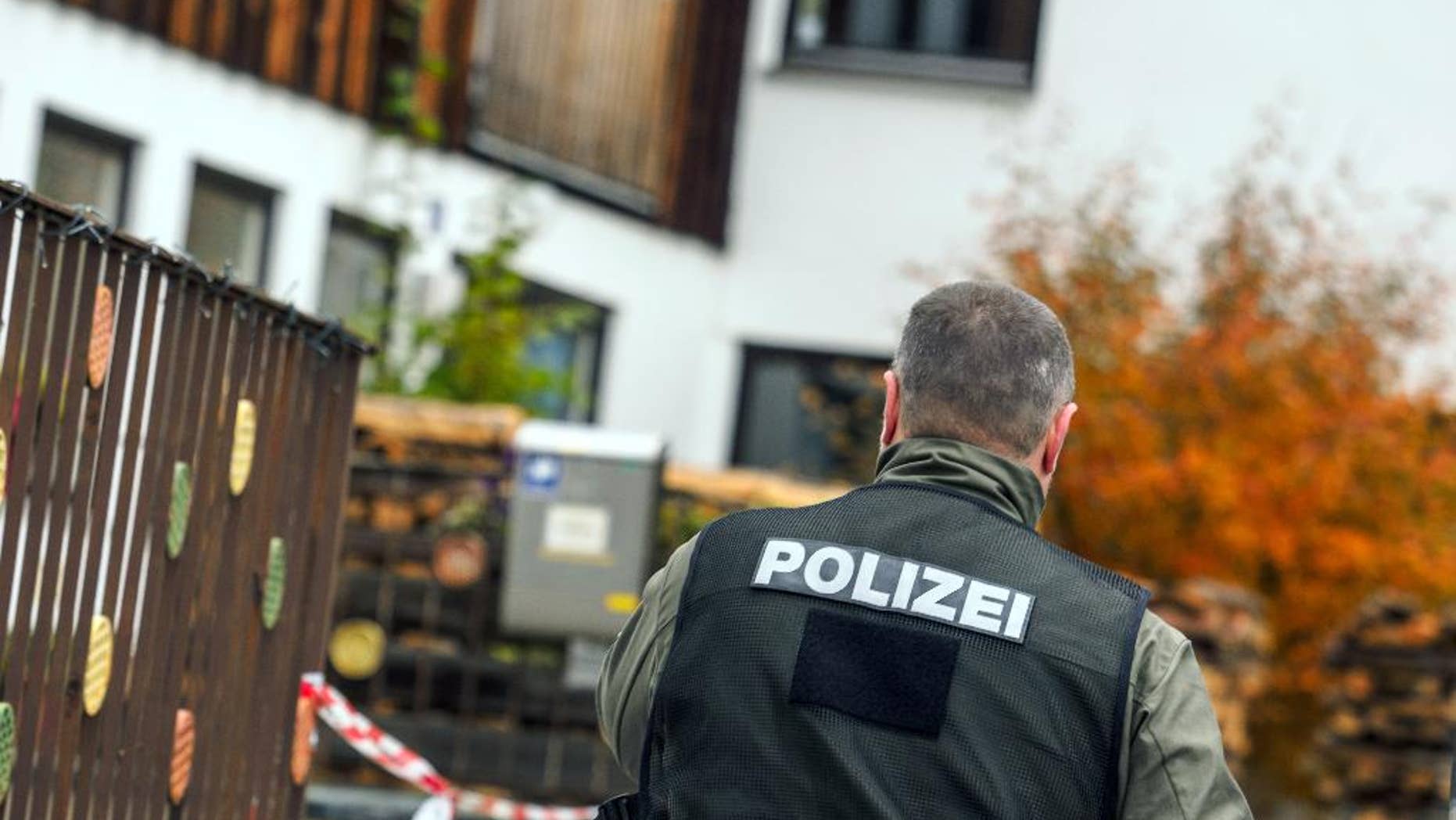 A policeman walks along the house in Georgensgmuend, Germany, Wednesday, Oct. 19, 2016, where an anti-government extremist opened fire on police in southern Germany during a raid in the morning in which they had planned to confiscate his weapons, and four officers were wounded, authorities said. The 49-year-old German man had legally possessed more than 30 weapons for hunting, but local authorities had revoked his license because he appeared increasingly unreliable, Bavarian Interior Minister Joachim Herrmann said. (Nicolas Armer/dpa via AP)