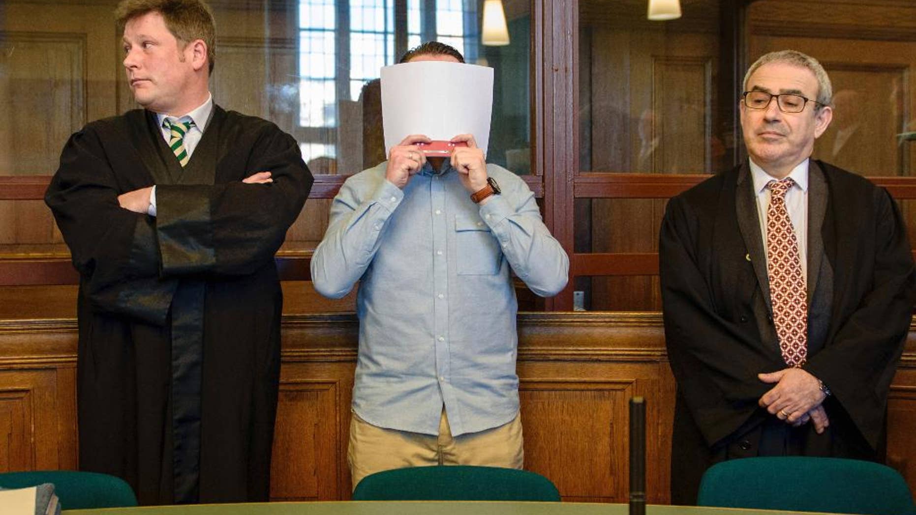 Accused Hamdi H., no full name given in line with Germany's privacy laws, covers his face before his verdict in a court in Berlin, Monday, Feb. 27, 2017, before he was sentenced for a life-term sentence for murder after killing a pedestrian when taking part in an illegal car race in downtown Berlin. (Gregor Fischer/dpa via AP)