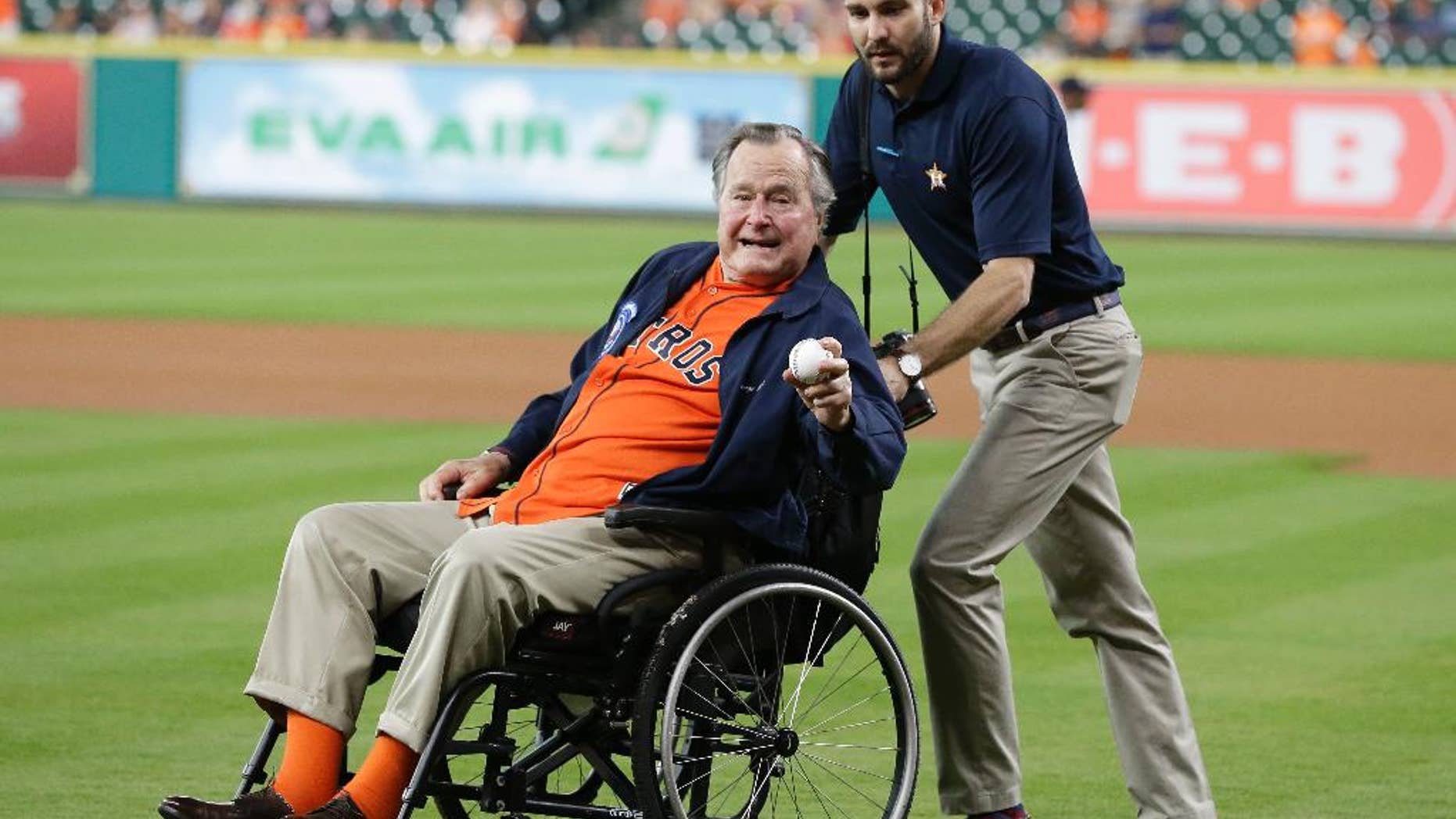 FILE - In this April 12, 2016 file photo, former President George H.W. Bush, left, shows his pitching grip as he wheeled out to the field to throw out the ceremonial first pitch to Houston Astros starting pitcher Collin McHugh before the baseball game against the Kansas City Royals in Houston. Fresh from his 92nd birthday, former President George H.W. Bush is enjoying himself in Maine after recovering from a fall at his home nearly a year ago. Bush led a group of 40 wounded warriors on a fishing trip at the helm of his speedboat Wednesday, June 15, 2016, three days after a low-key birthday celebration. (AP Photo/Pat Sullivan, File)