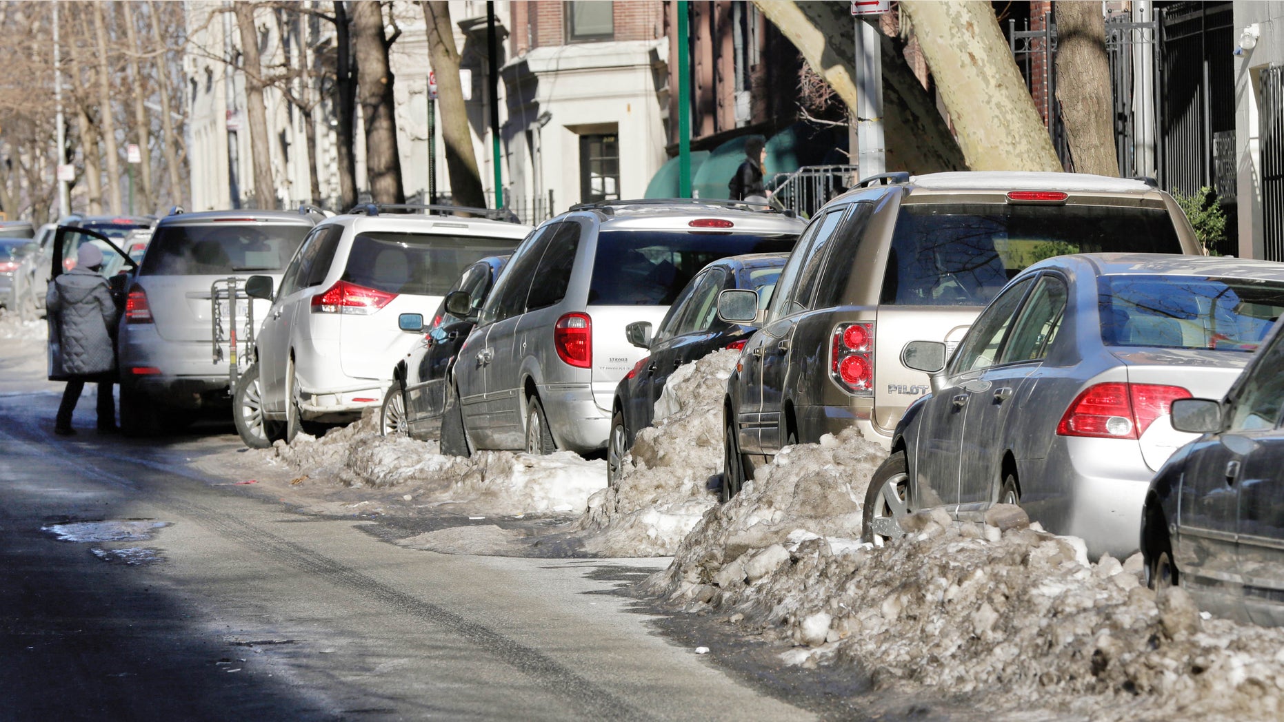 Some snow-bound cars line one side of a street in New York's Upper West Side neighborhood, Wednesday, Feb. 25, 2015. For the first time in weeks, New York City's alternate side parking rules are back in place after being suspended to allow for snow removal. (AP Photo/Richard Drew)