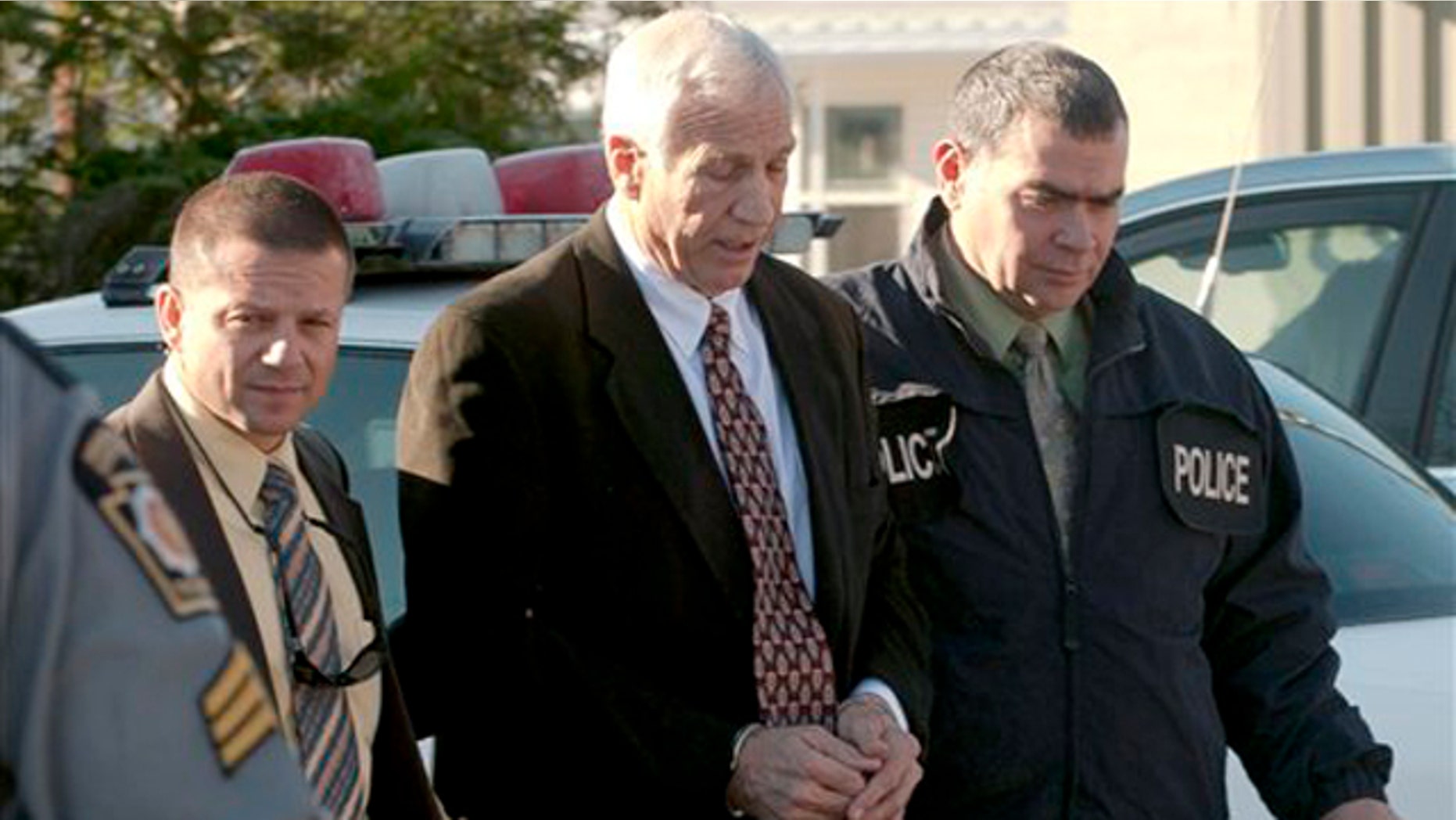 Nov. 5: In this photo provided by the Pennsylvania Office of Attorney General, former Penn State football defensive coordinator Gerald "Jerry" Sandusky, is escorted in handcuffs to a waiting police car in Bellefonte, Pa.
