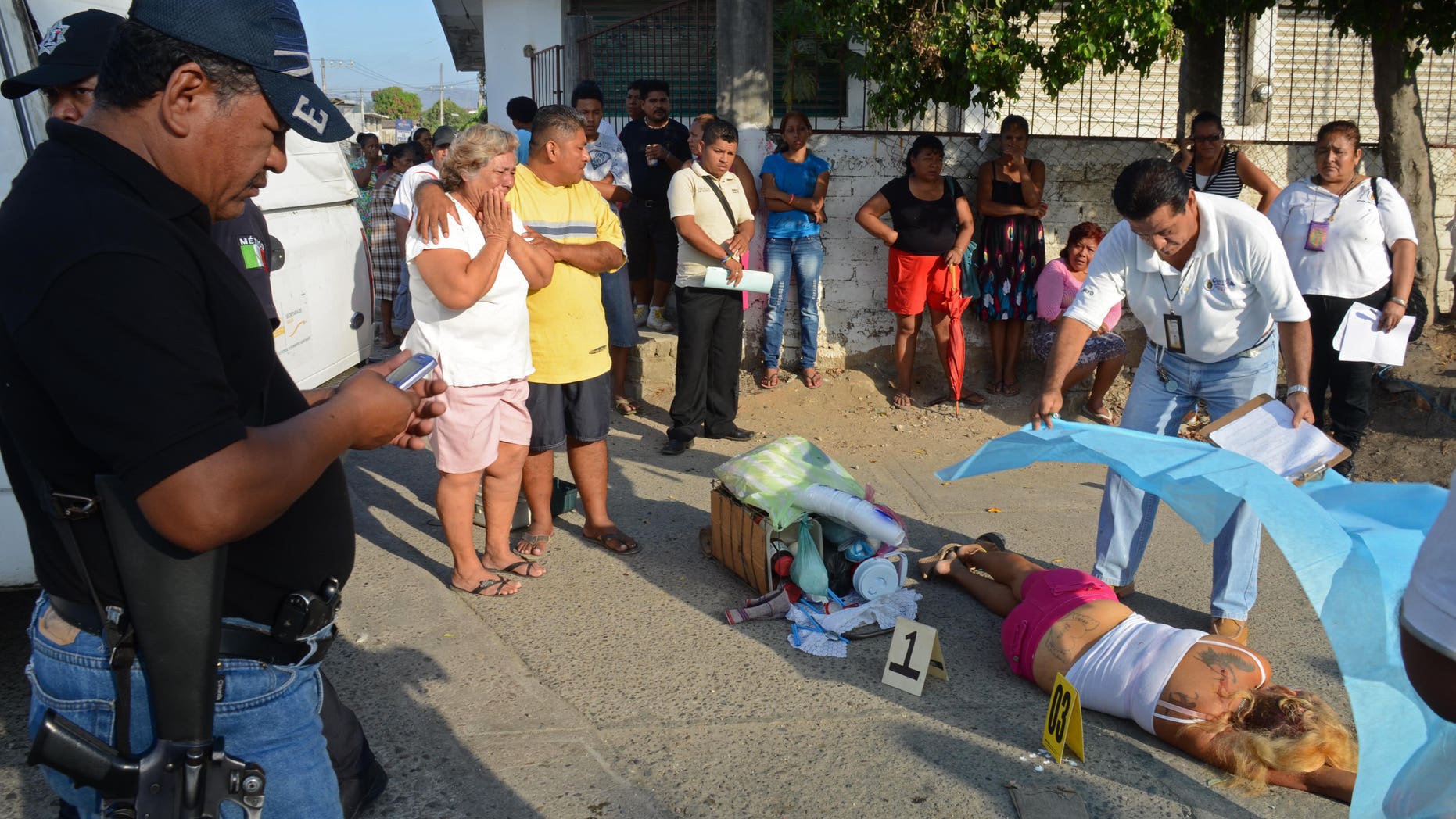 A forensic worker covers the body of a woman who was shot dead by assailants, whose daughter was also killed, while she was selling coffee on a street corner in Acapulco, Mexico, Tuesday, April 9, 2013. Violence, kidnappings and extortions carried out by drug cartels continue to plague this Pacific resort city which has witnessed a large increase in violent crimes during the past years. (AP Photo/Bernandino Hernandez)