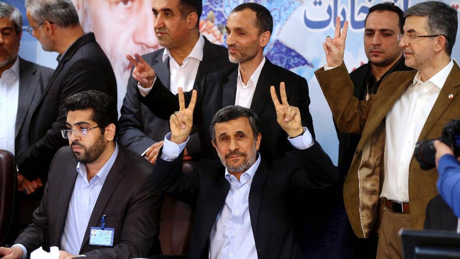Former Iranian President Mahmoud Ahmadinejad, seated center, flashes the victory sign as he is registering candidacy for the upcoming presidential elections at the Interior Ministry in Tehran, Iran, Wednesday, April 12, 2017. Ahmadinejad on Wednesday unexpectedly filed to run in the country's May presidential election, contradicting a recommendation from the supreme leader to stay out of the race. (AP Photo/Ebrahim Noroozi)