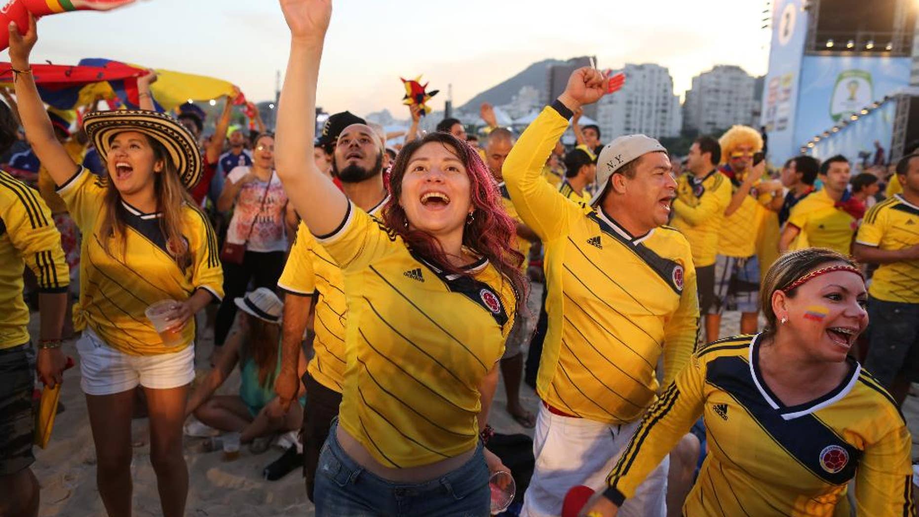 Colombia soccer fans celebrate the goal scored by their team as they watch a live telecast of their team's World Cup match with Japan inside the FIFA Fan Fest area on Copacabana beach, in Rio de Janeiro, Brazil, Tuesday, June 24, 2014. After 12 days of competition, Colombia has already reached the second round with a game to spare, won two matches at the tournament for the first time, and played with a vigor that has made the team one of the most exciting to watch in Brazil. (AP Photo/Leo Correa)