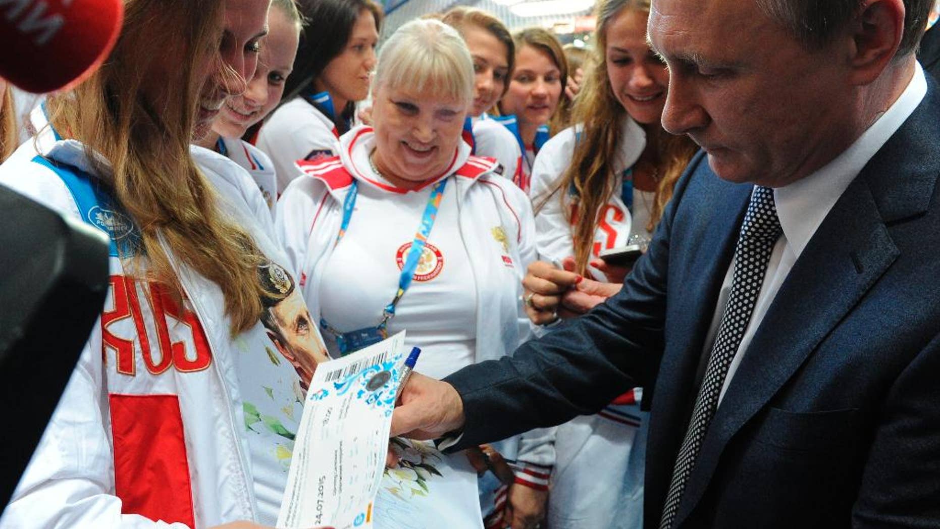 FILE- In this Friday, July 24, 2015 file photo, Russian President Vladimir Putin, right, signs autographs during his meeting with Russian athletes before the opening ceremony of the World Swimming Championships at the Kazan Arena stadium in Kazan, Russia. Donald Trump’s statement that Russian President Vladimir Putin enjoys an 82 percent approval rating among his people wasn’t hyperbole. Russia’s two main polling agencies consistently give the man in the Kremlin ratings that would be the envy of Trump or his rival in the U.S. presidential election, Hillary Clinton. (Mikhail Klimentyev/RIA-Novosti, Kremlin Pool Photo via AP, File)