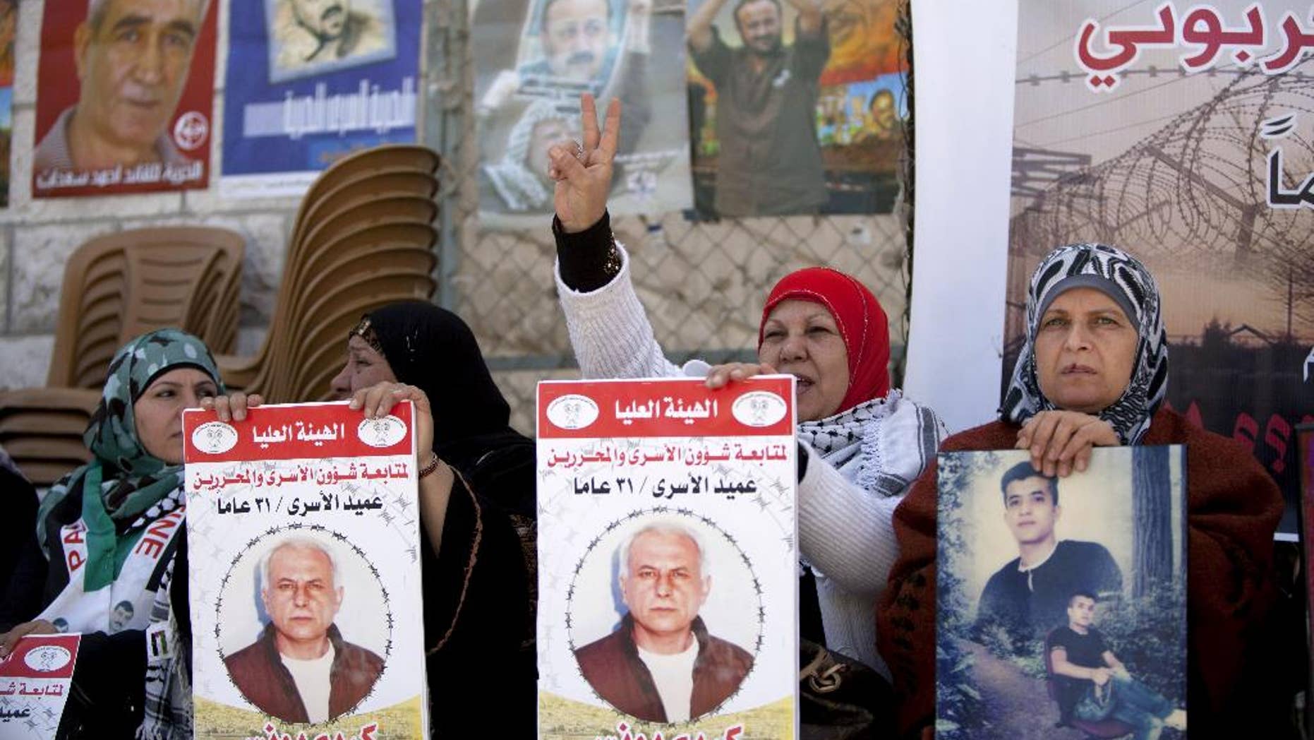 Women hold portraits of Palestinian prisoners held in Israeli jails during a rally calling for their release in the West Bank city of Ramallah, Tuesday, April 1, 2014. Arabic on the posters read, "Dean of prisoners, Karim Younis, 21 years in prison." (AP Photo/Majdi Mohammed)