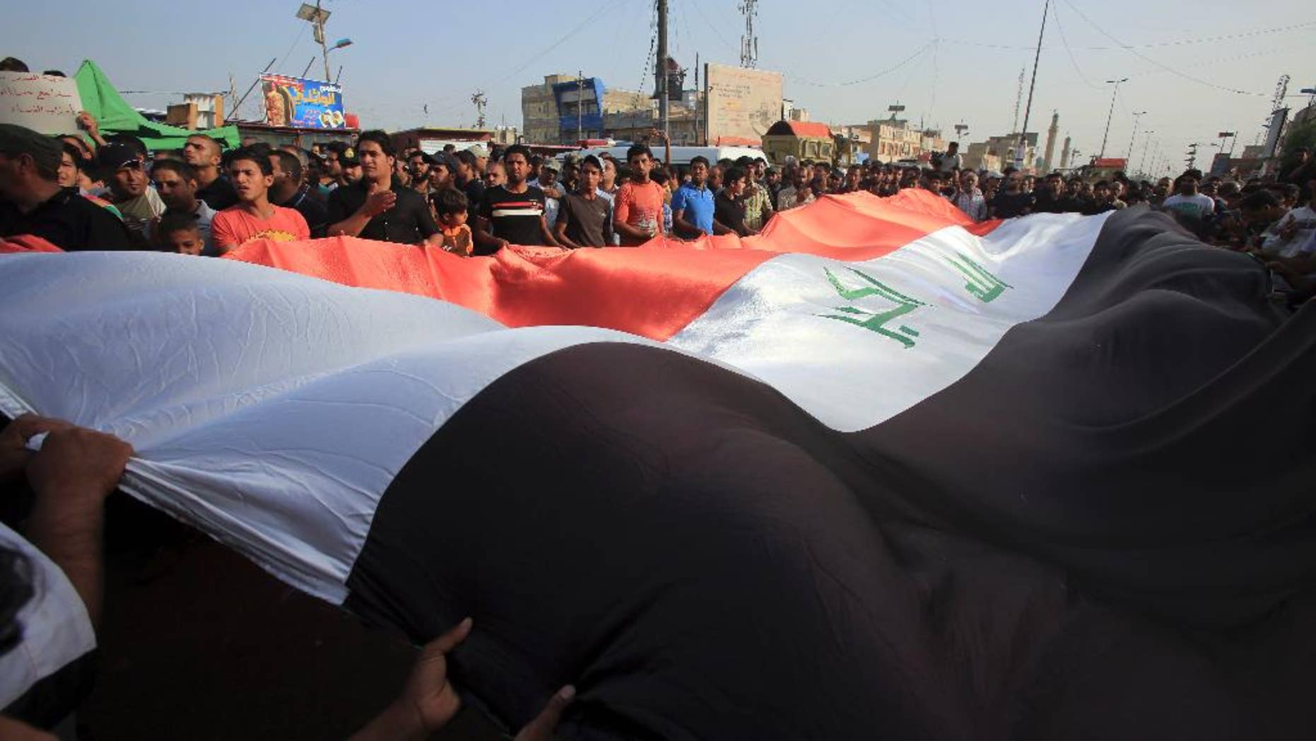 Protesters wave a giant Iraq flag as they chant anti-government slogans during a demonstration against the security forces' failure to protect them from car bombs Thursday.