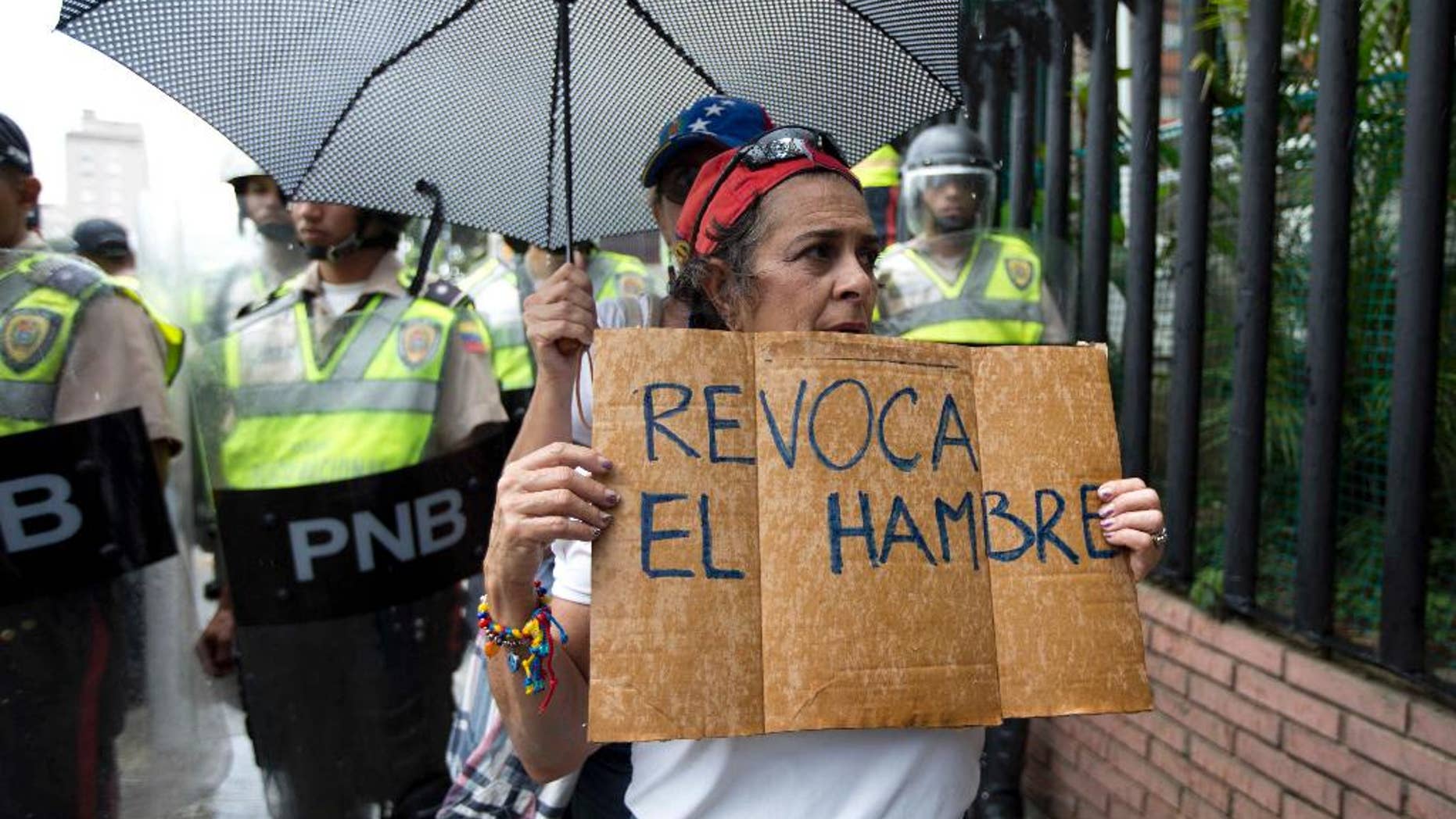 FILE - In this July 27, 2016, file photo, a woman holds a sign with a message that in reads in Spanish "Revoke hunger" during a protest march in Caracas, Venezuela. Venezuela's electoral authorites, on Monday,Aug. 1, have validated the signatures for a recall referendum process against President Nicolas Maduro. (AP Photo/Ariana Cubillos, File)