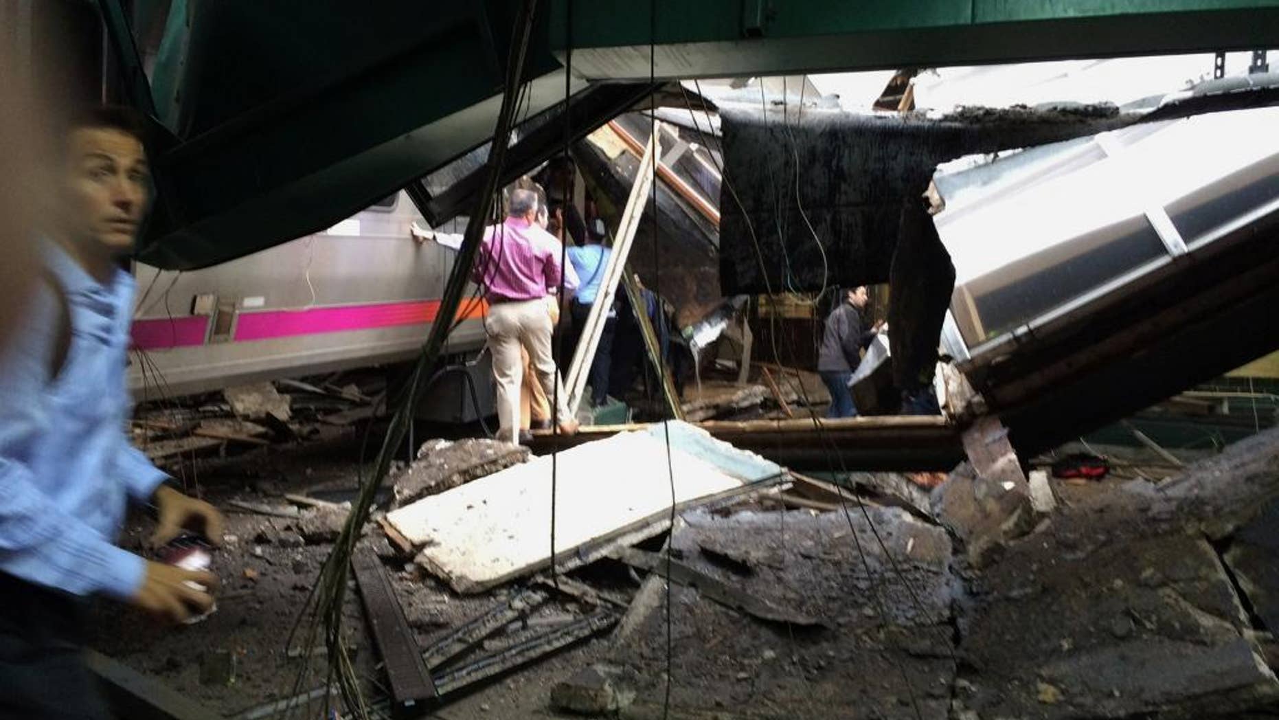 In a photo provided by William Sun, people examine the wreckage of a New Jersey Transit commuter train that crashed into the train station during the morning rush hour in Hoboken,, N.J., Thursday, Sept. 29, 2016. The crash caused an unknown number of injuries and witnesses reported seeing one woman trapped under concrete and many people bleeding. (William Sun via AP)