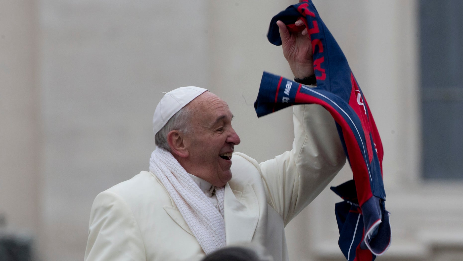 Pope Francis grabs a shirt thrown to him by faithful as he leaves at the end of his weekly general audience in St. Peter's Square at the Vatican, Wednesday, Nov. 27, 2013. A chilly Pope Francis has cheered the thousands of pilgrims who braved a cold snap belting Italy to attend his weekly general audience, saying they were courageous to come out. (AP Photo/Alessandra Tarantino)