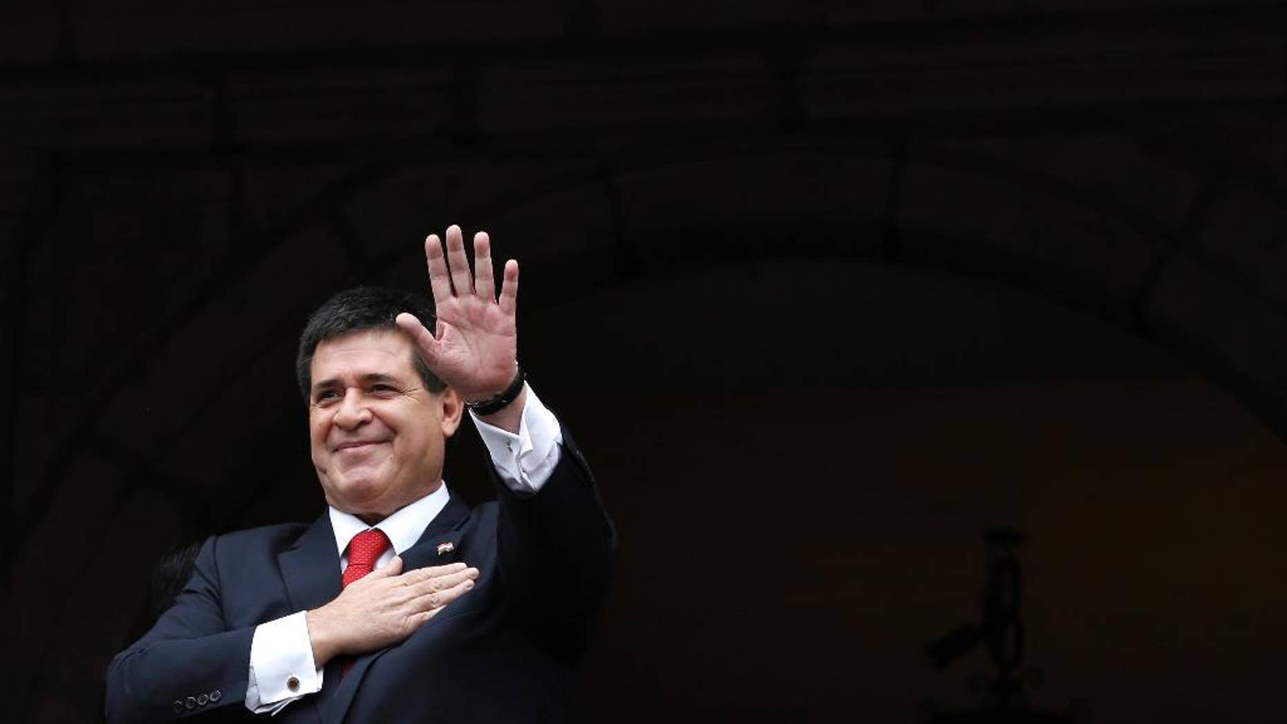 FILE - In this Nov. 21, 2014 file photo, Paraguay's President Horacio Cartes waves from a government palace balcony, in Quito, Ecuador. President Cartes said Monday, April 17, 2017, that he will not be a candidate in the 2018 election even if Congress approves a constitutional amendment to allow a second term. (AP Photo/Dolores Ochoa, File)